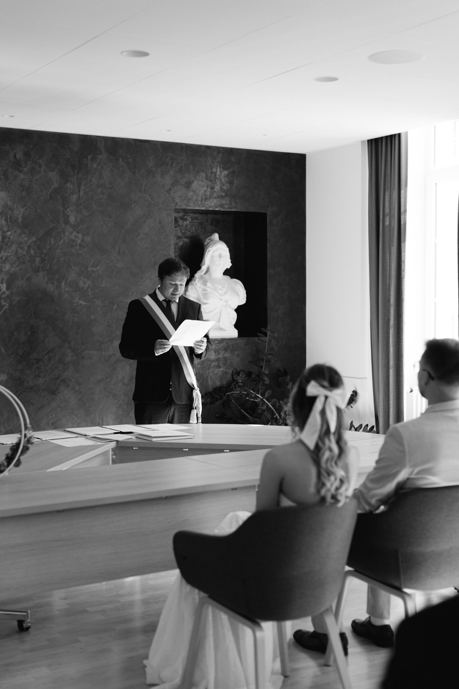 Photo en noir et blanc d'un officiant en train de lire lors d'une cérémonie de mariage civil à l'hôtel de Ville.