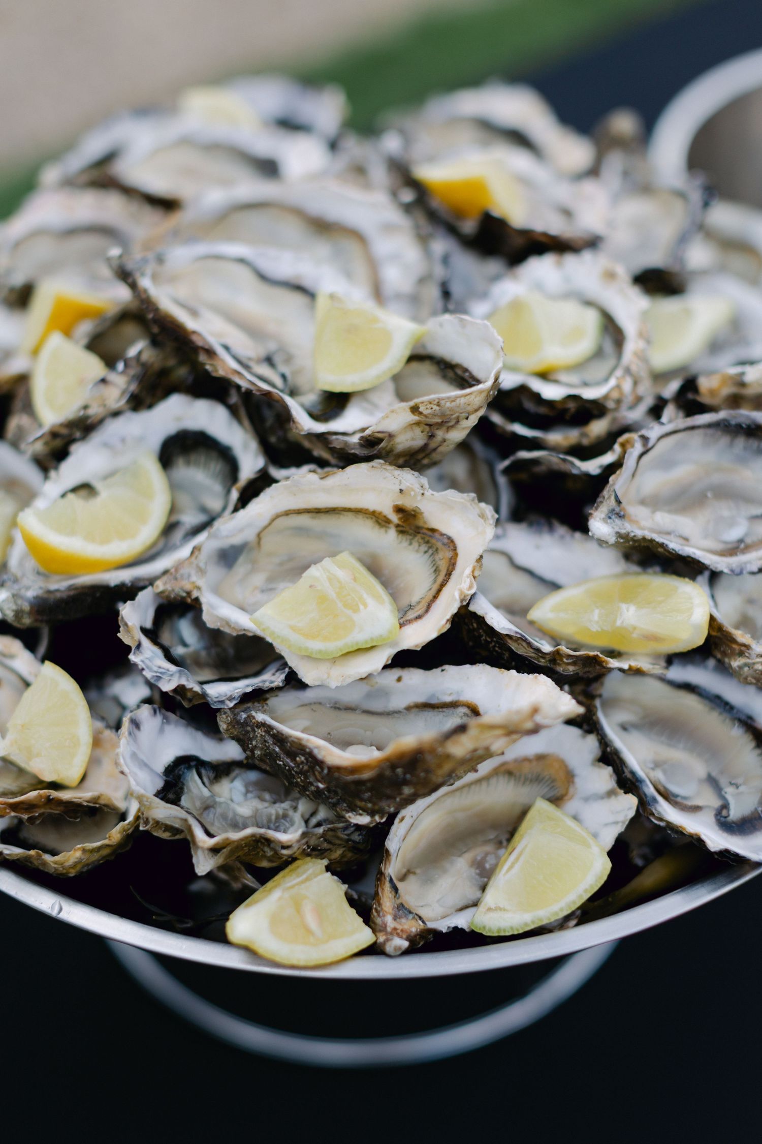 Huîtres fraîches décortiquées avec des quartiers de citron servies sur un élégant plateau de fruits de mer à plusieurs niveaux.