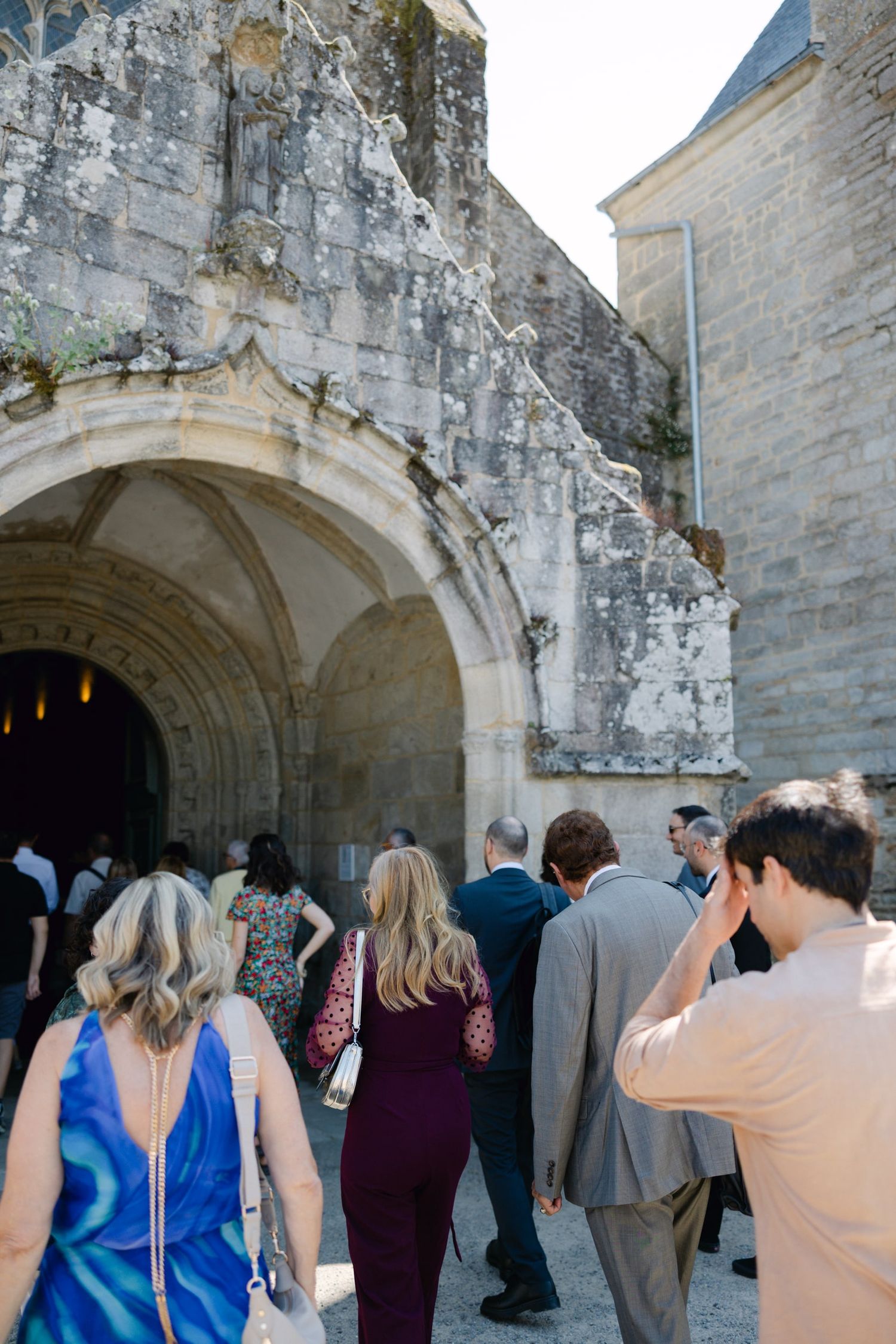 Wedding guests entering an ancient stone archway at a historic French chateau venue.