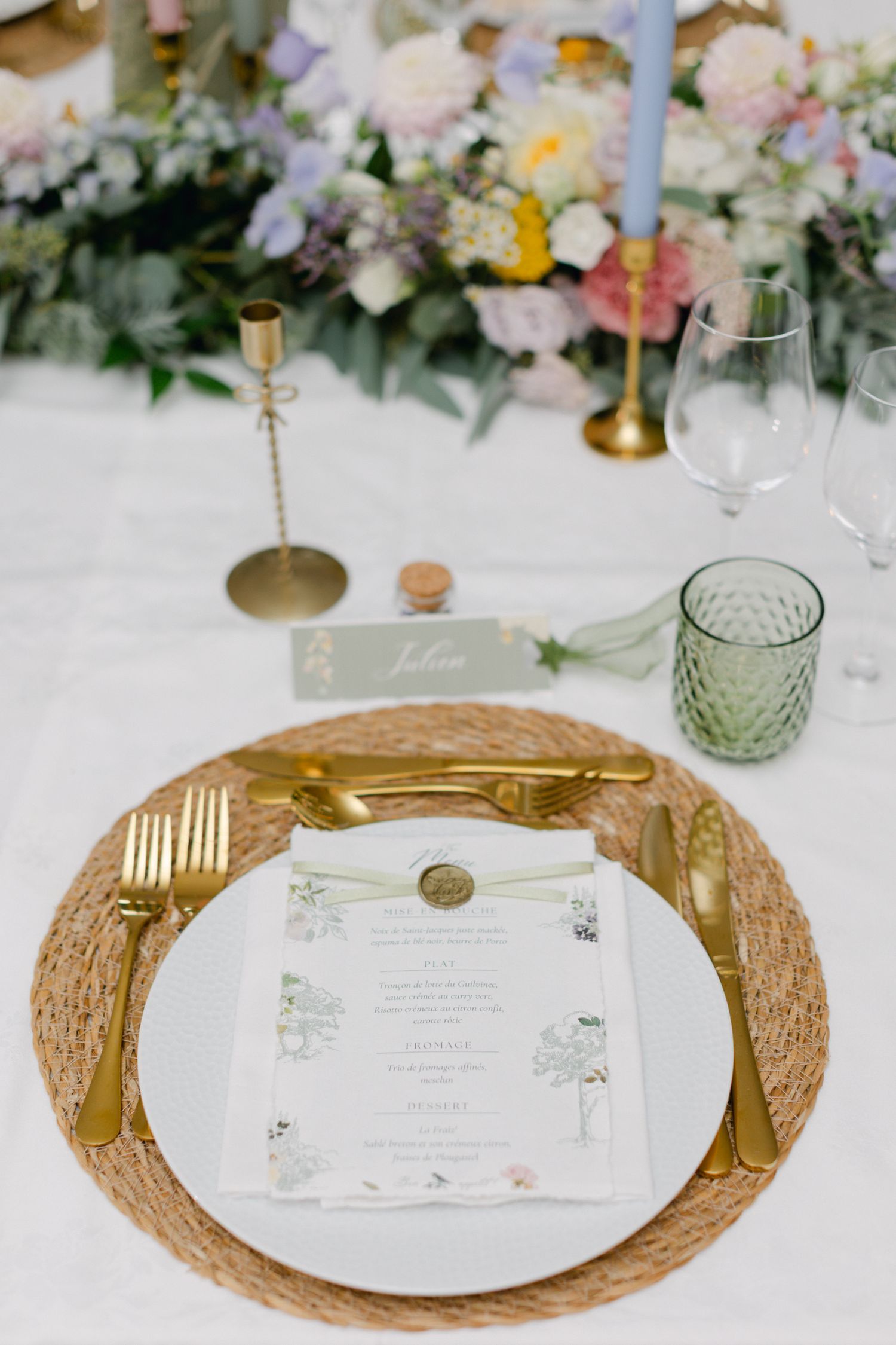 Cadre de mariage élégant avec couverts en or, assiette de chargeur tissé, carte de menu floral et sceau de cire.