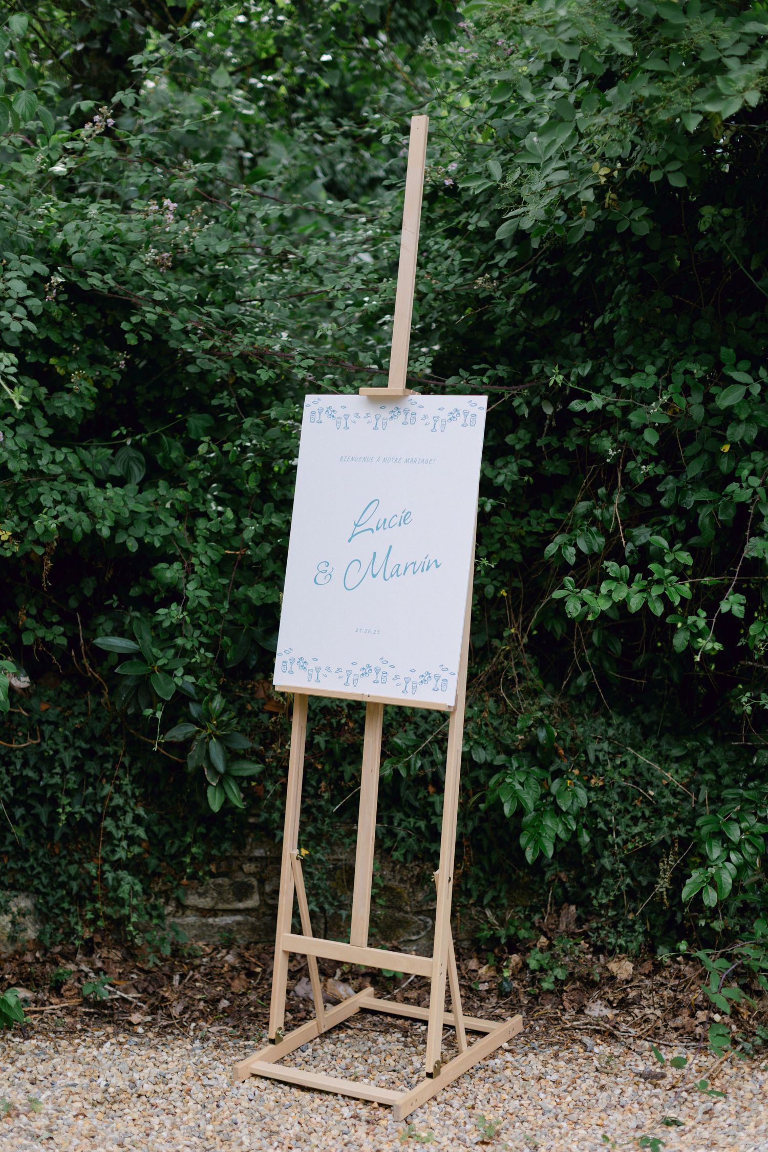 Chevalet en bois affichant un élégant panneau de bienvenue de mariage pour Luca et Marion dans le cadre du jardin.