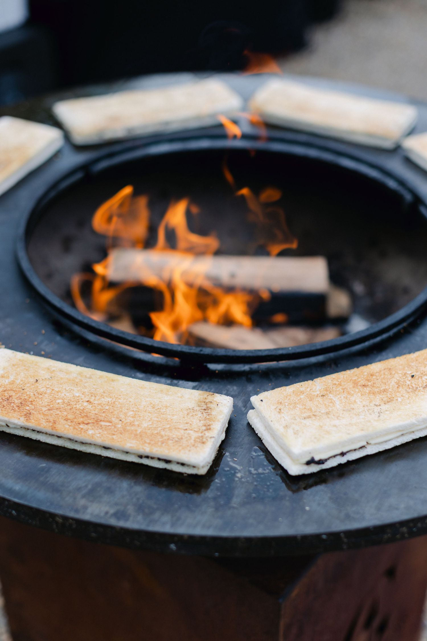 Tranches de pain grillées autour d'un foyer à flamme ouverte lors d'une réception de mariage en plein air.