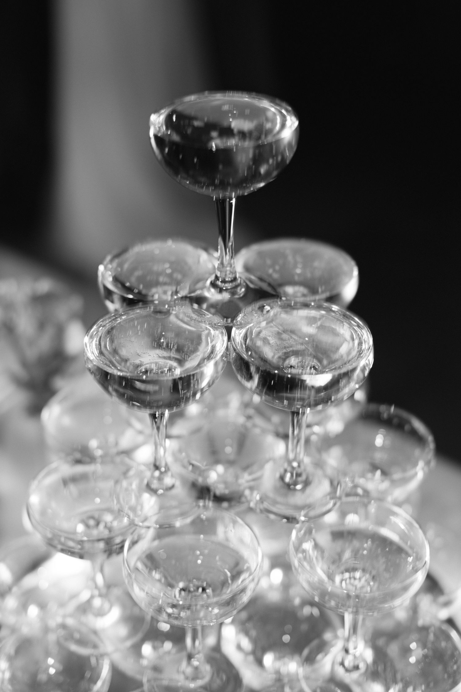 Élégante pyramide de verres coupés à champagne empilés pour les toasts de réception de mariage en noir et blanc.