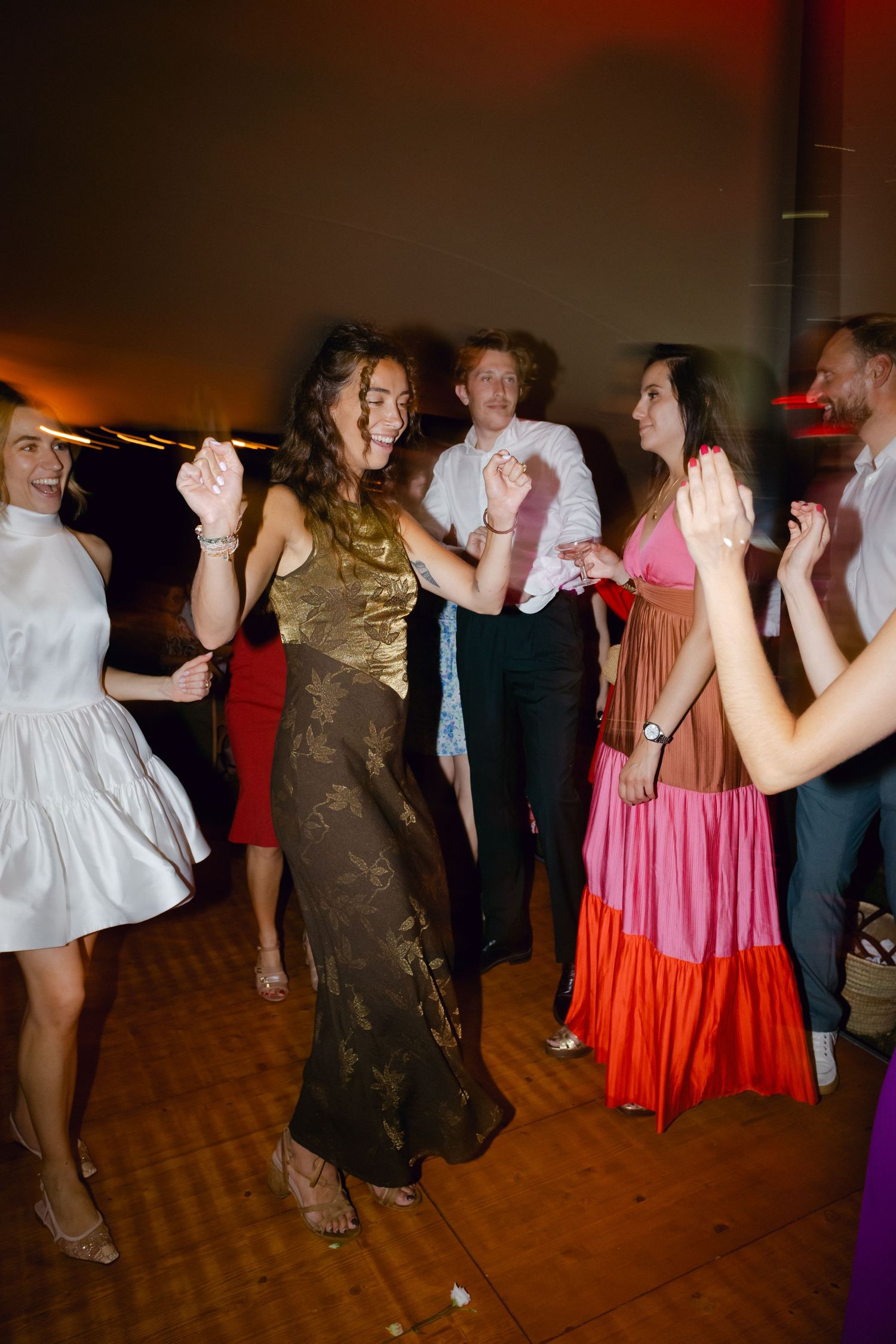 Des invités en tenue élégante dansant joyeusement lors d'une réception de mariage sous une lumière ambiante chaleureuse.