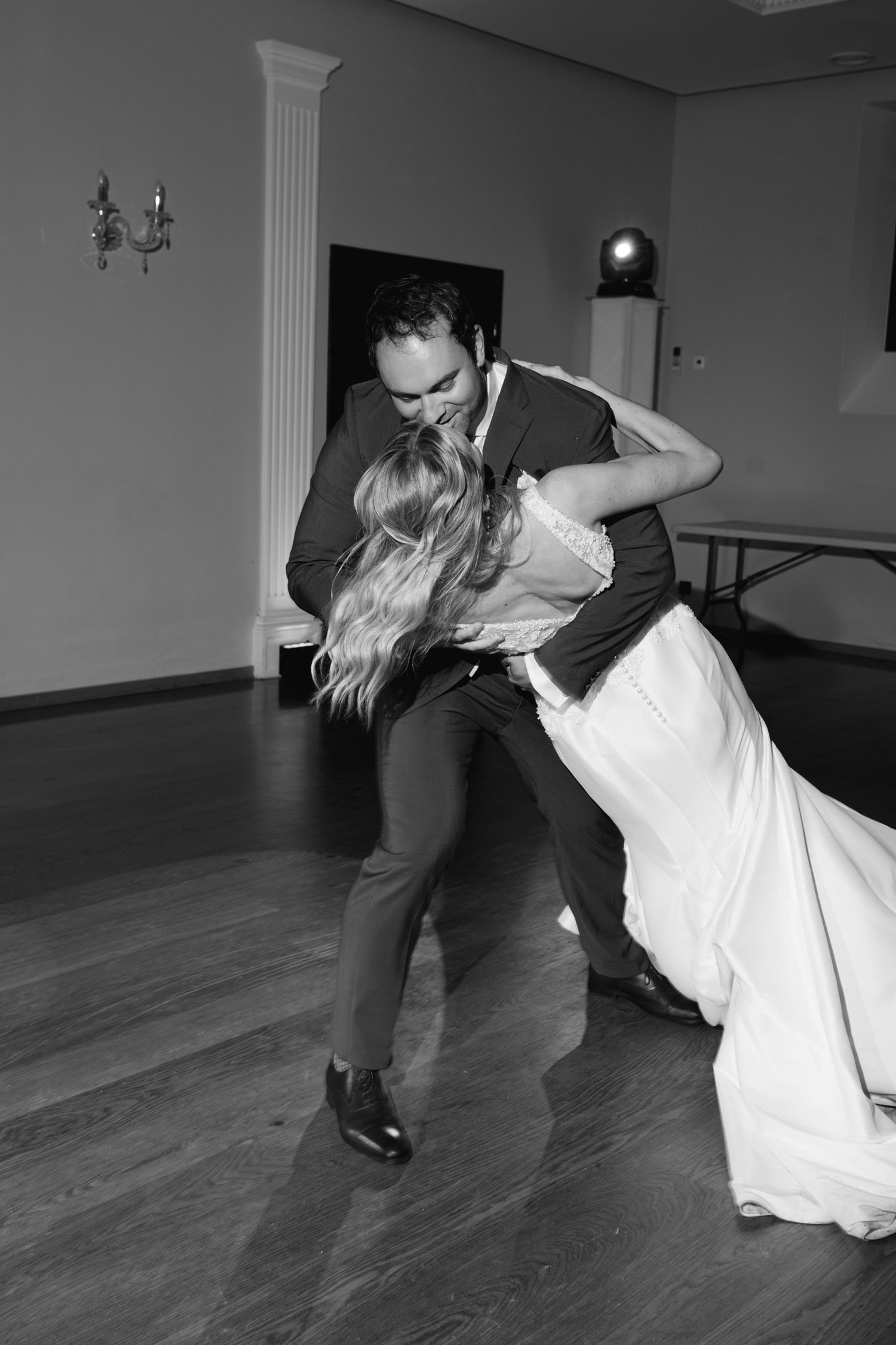 Le marié plonge dramatiquement la mariée sur la piste de danse lors de la première danse romantique à la réception de mariage en noir et bla
