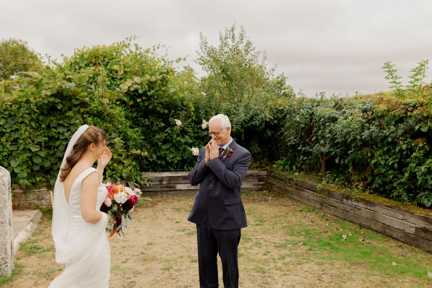 Outdoor wedding photoshoot in a scenic garden setting with guests and couple captured in natural candid moments.
