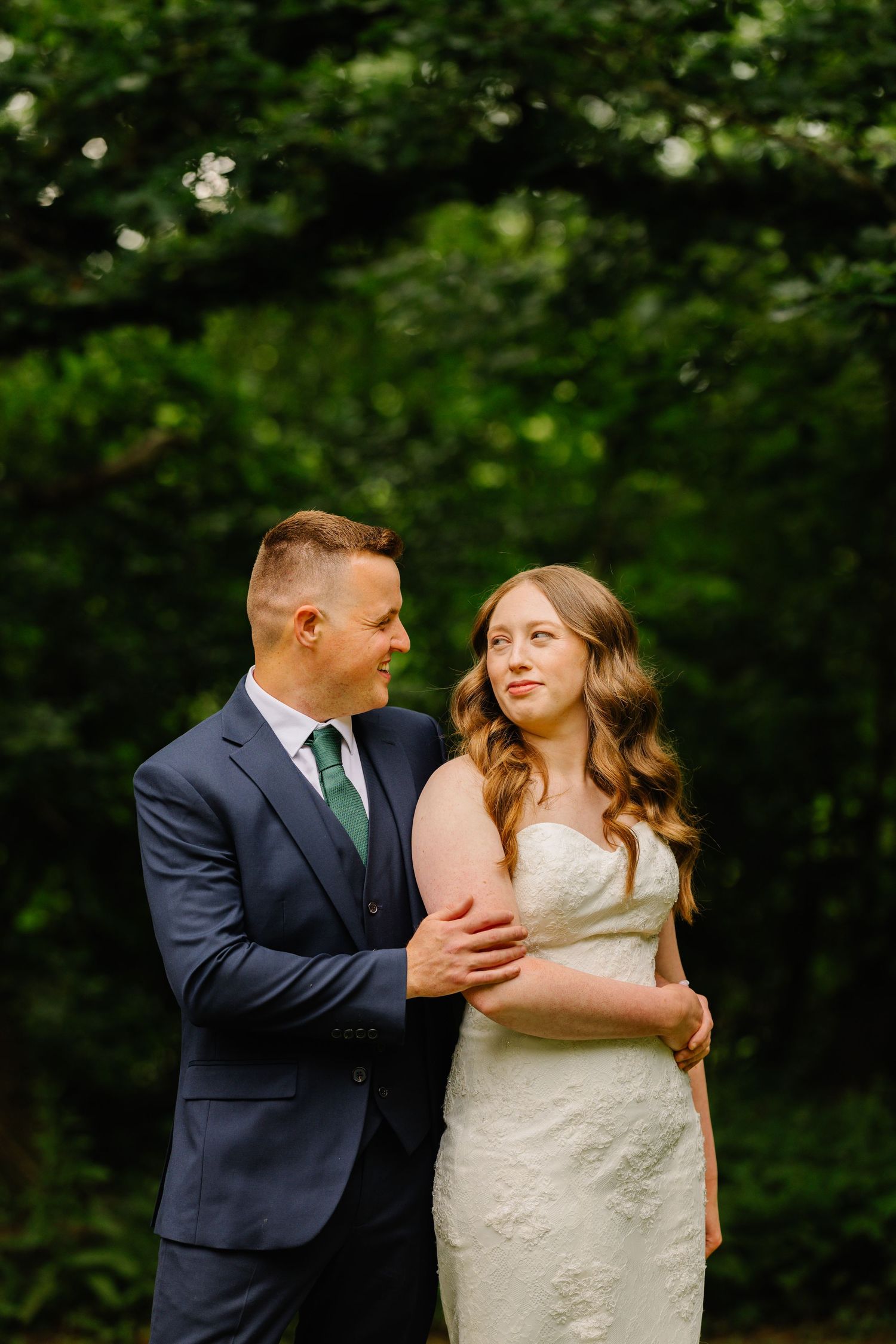 A romantic outdoor portrait of a couple surrounded by lush green foliage.