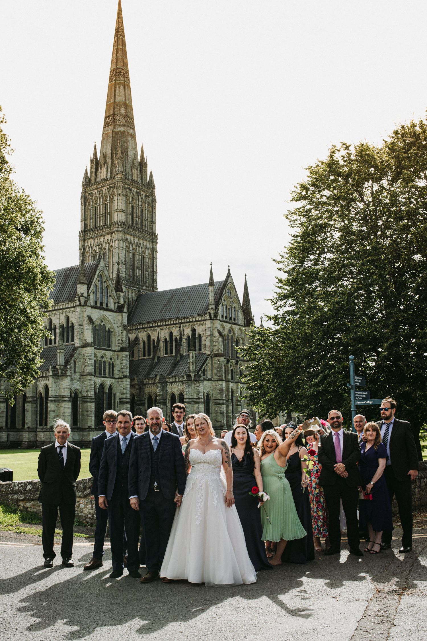 Wedding group photo in front of gothic cathedral with tall spire.