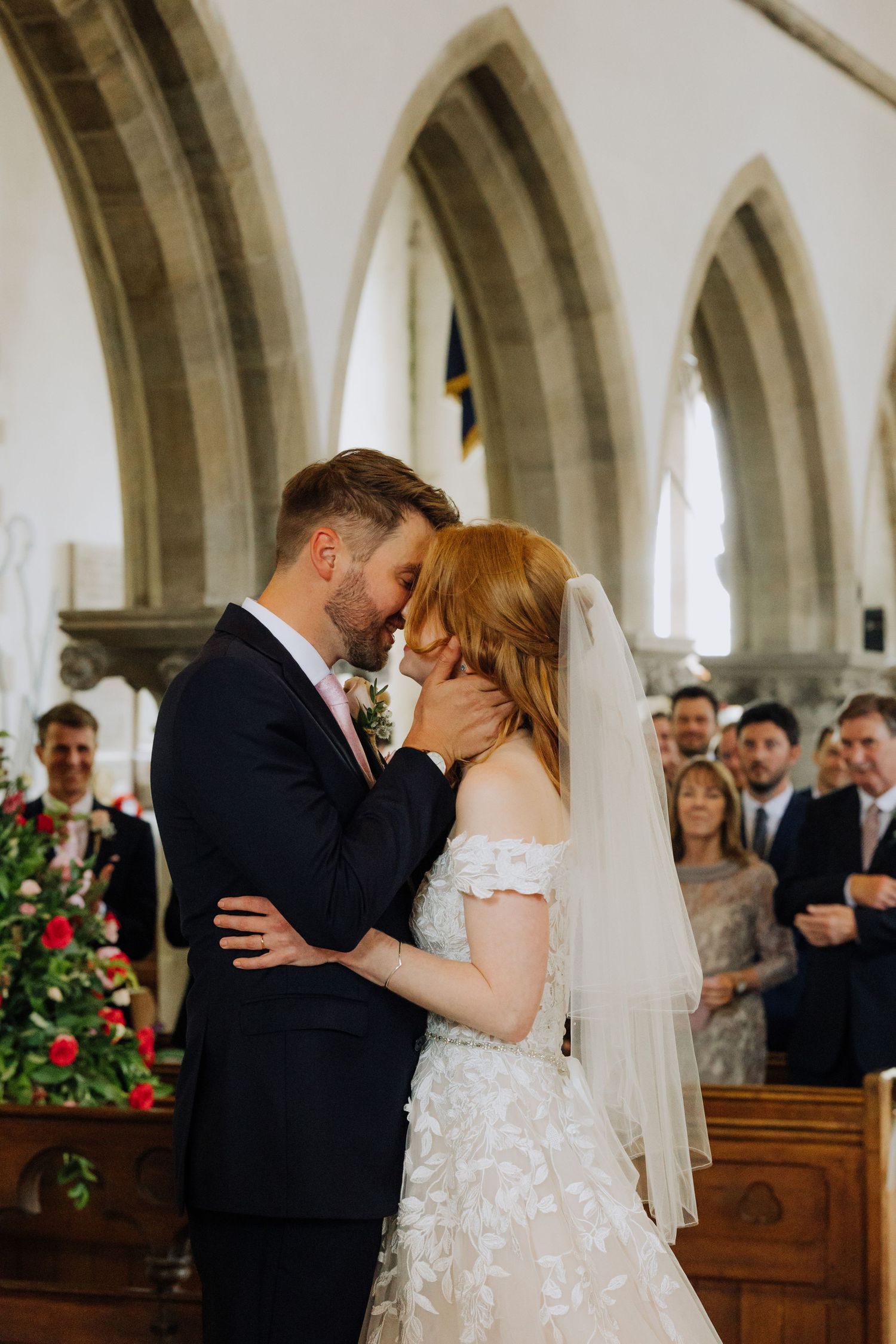 A romantic first kiss during a wedding ceremony in a traditional stone church.