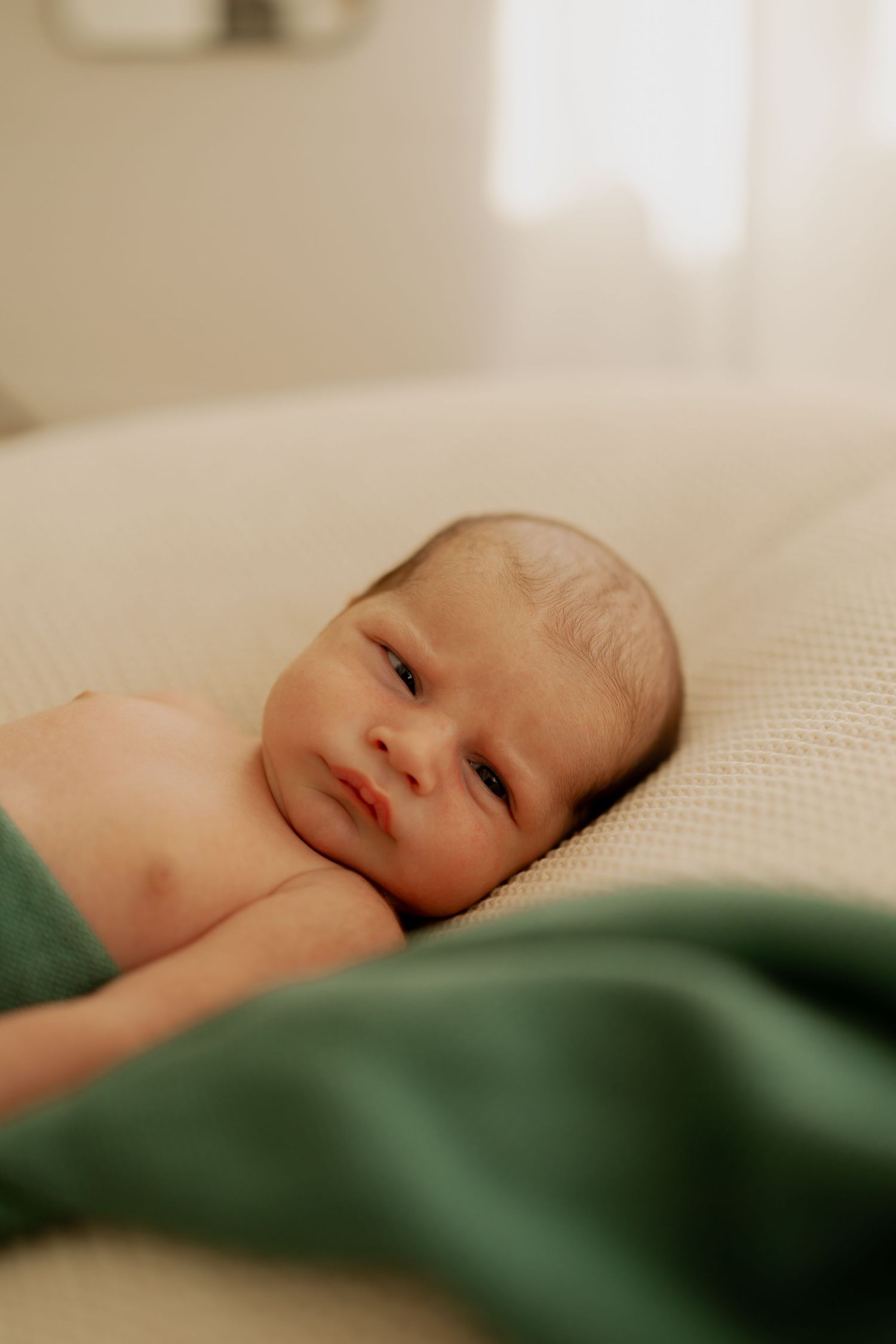 A close-up series of a sleeping baby on white bedding with green blanket edge visible in the frame.