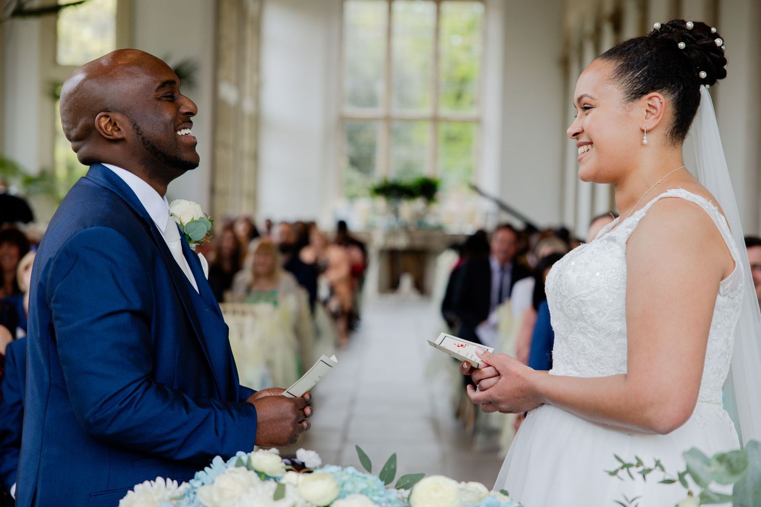 A couple exchanges vows during their wedding ceremony in a bright indoor venue.