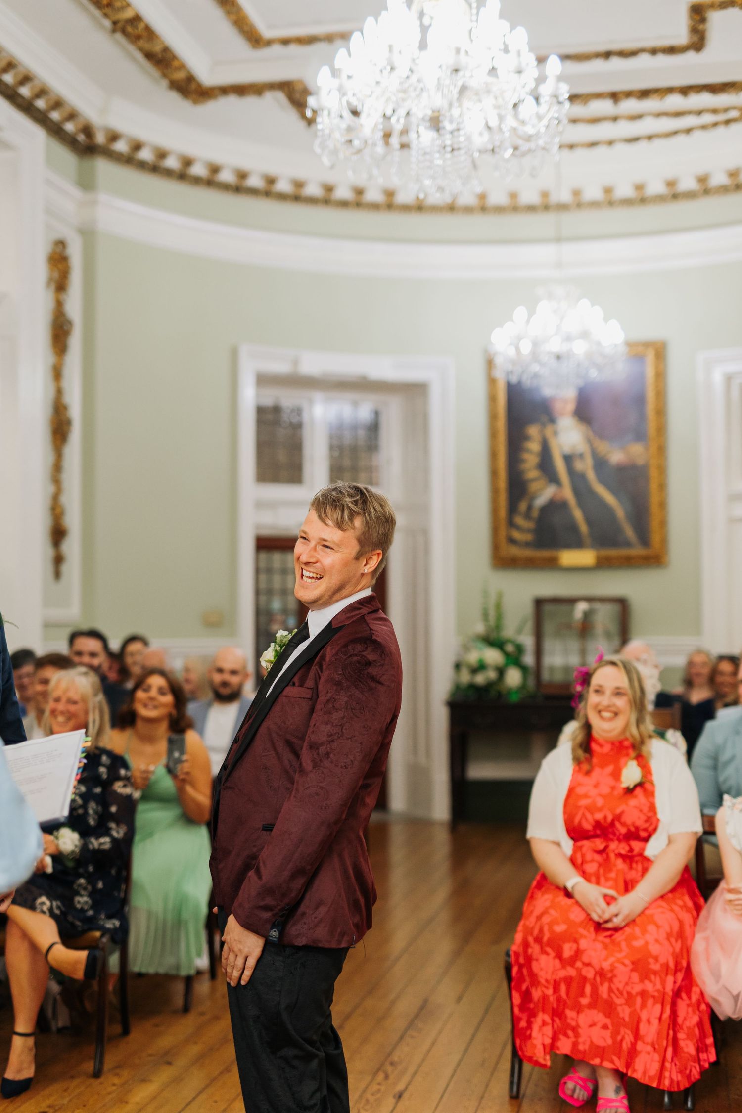 An elegant wedding reception in a historic room with ornate chandelier and decorative moldings.