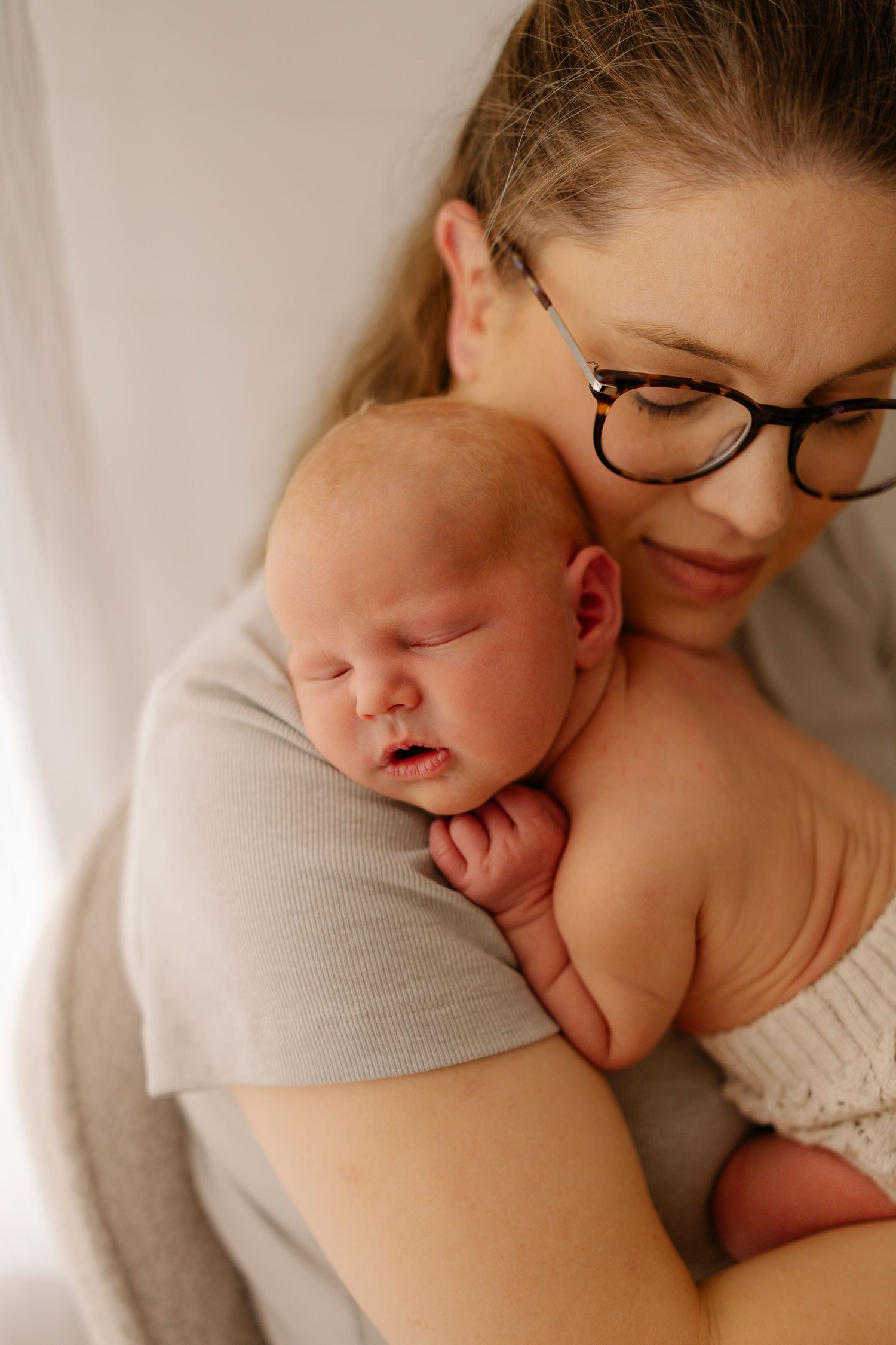 Tender moment between mother and sleeping baby in soft natural light.