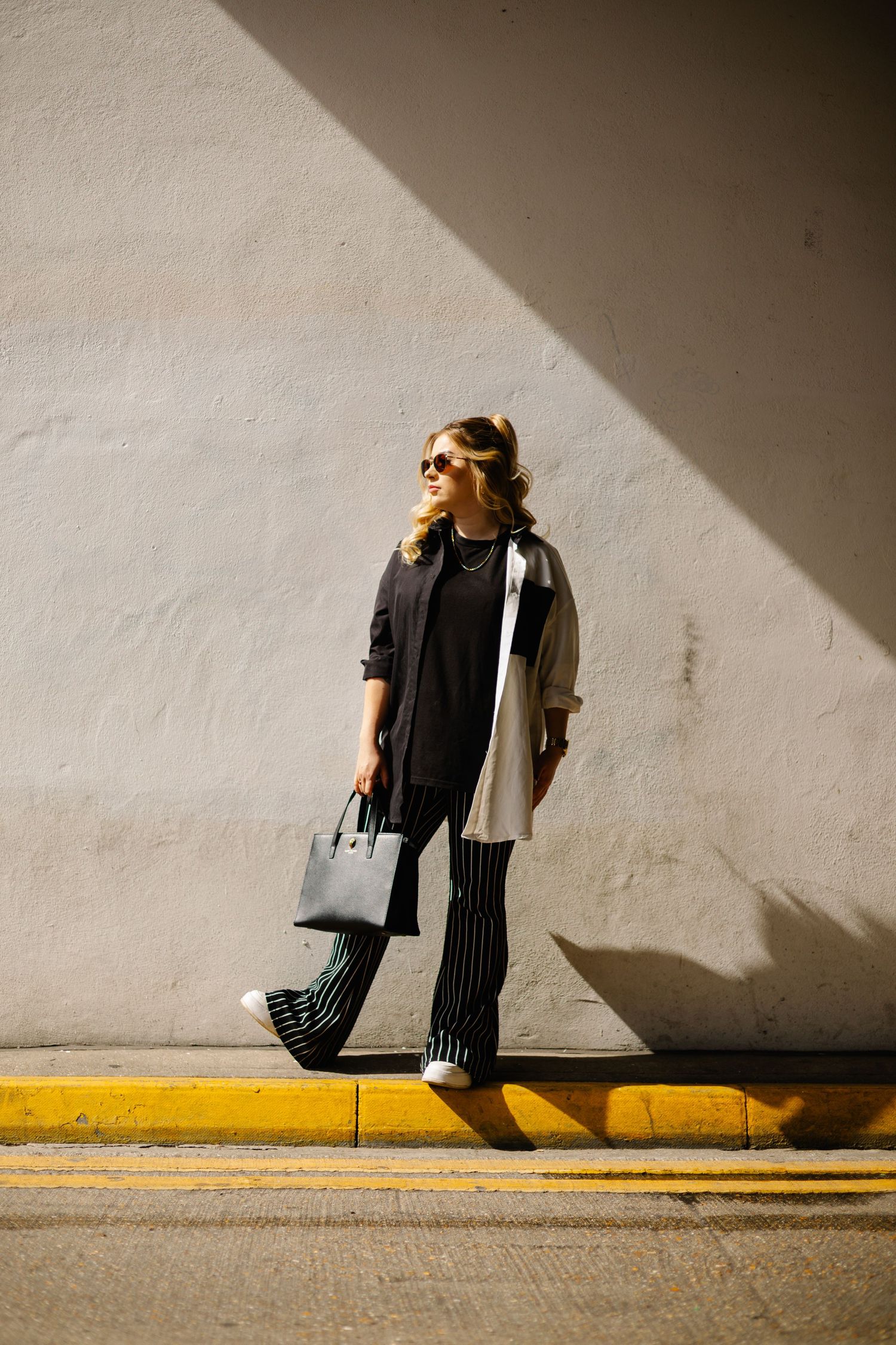 A sequence of four artistic photographs showing dramatic shadows against a white wall with a person in casual attire.