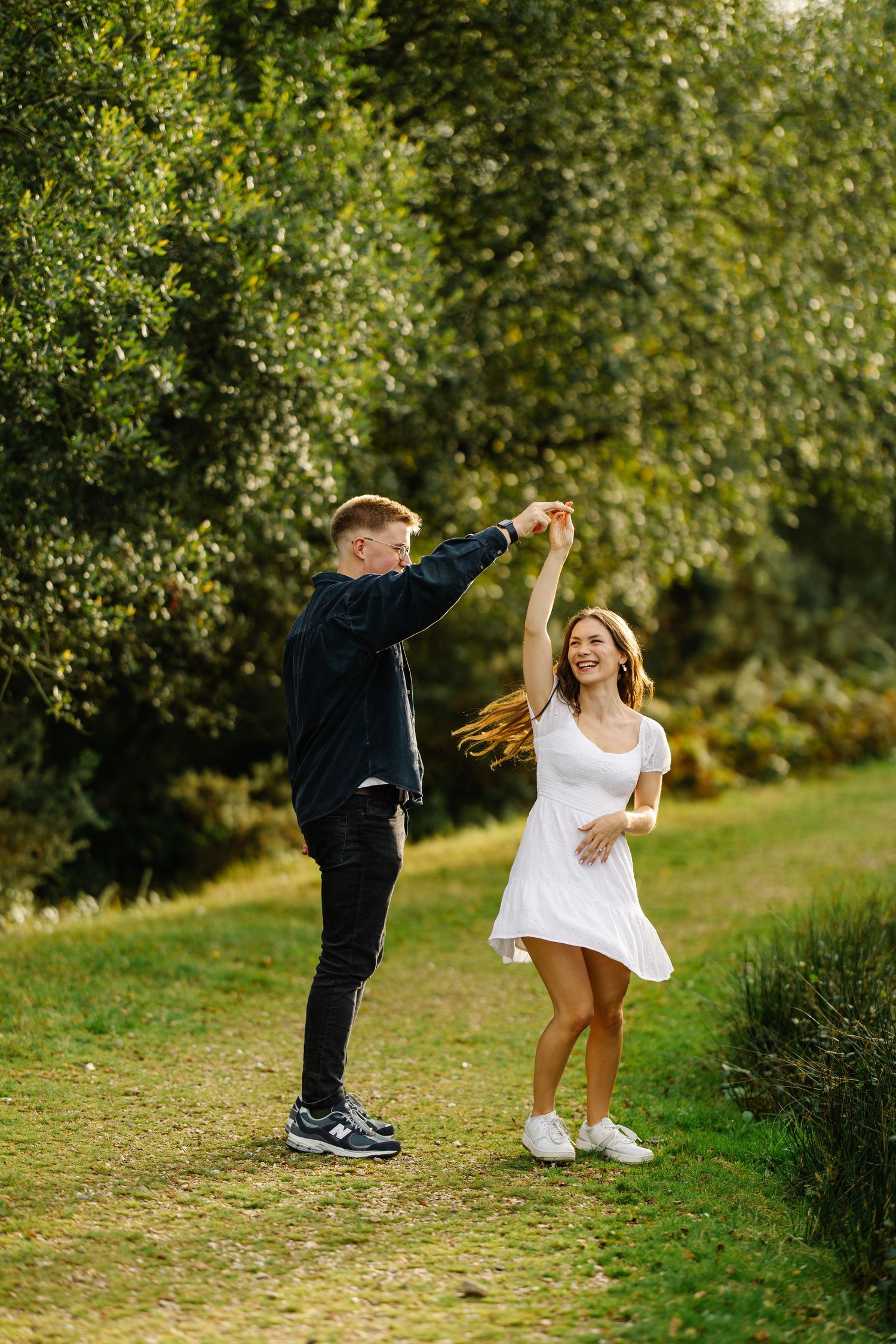 A couple dances together on a nature trail surrounded by lush greenery.