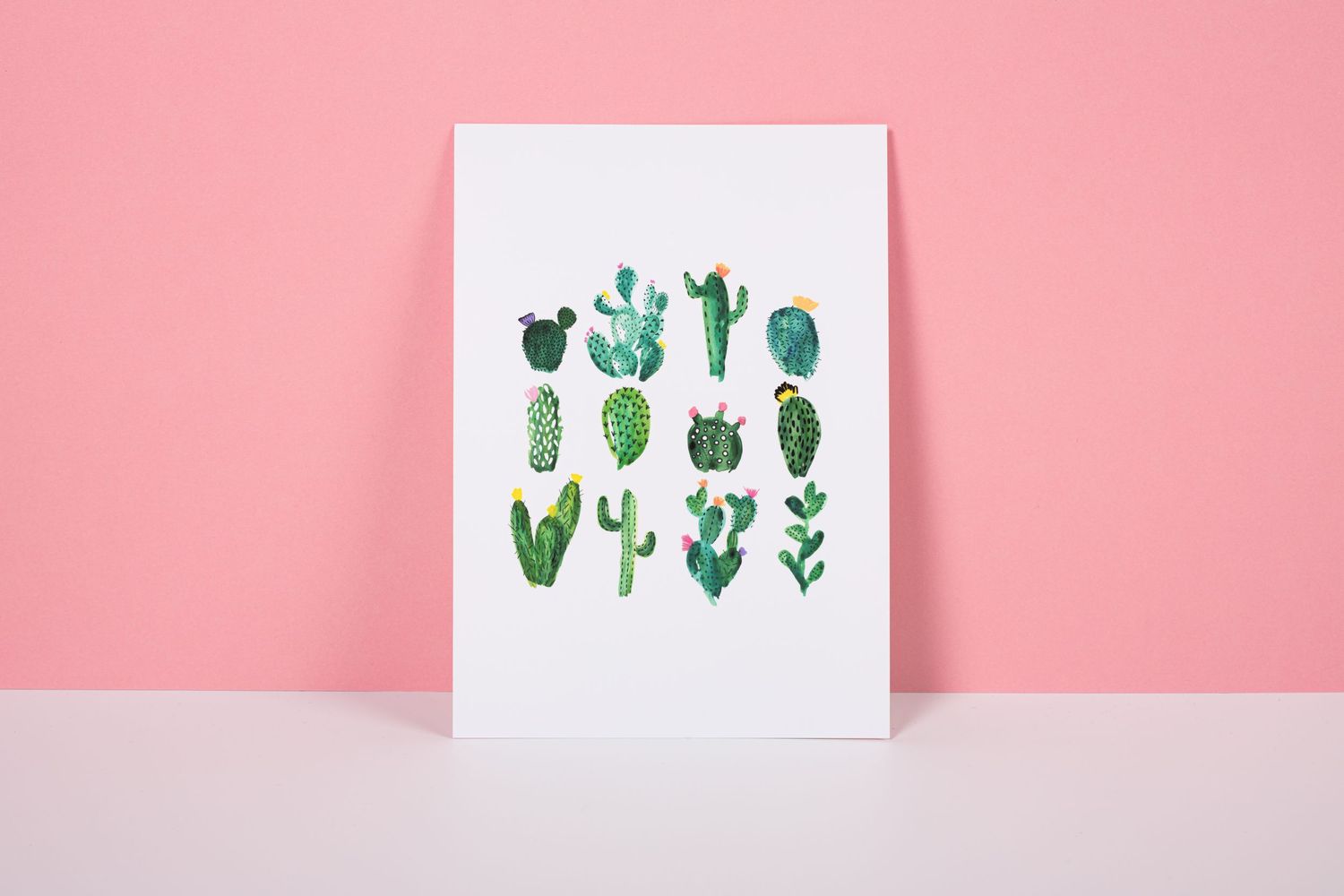 Decorative green cacti and plant watercolor illustrations arranged on pink background create a whimsical minimalist pattern.