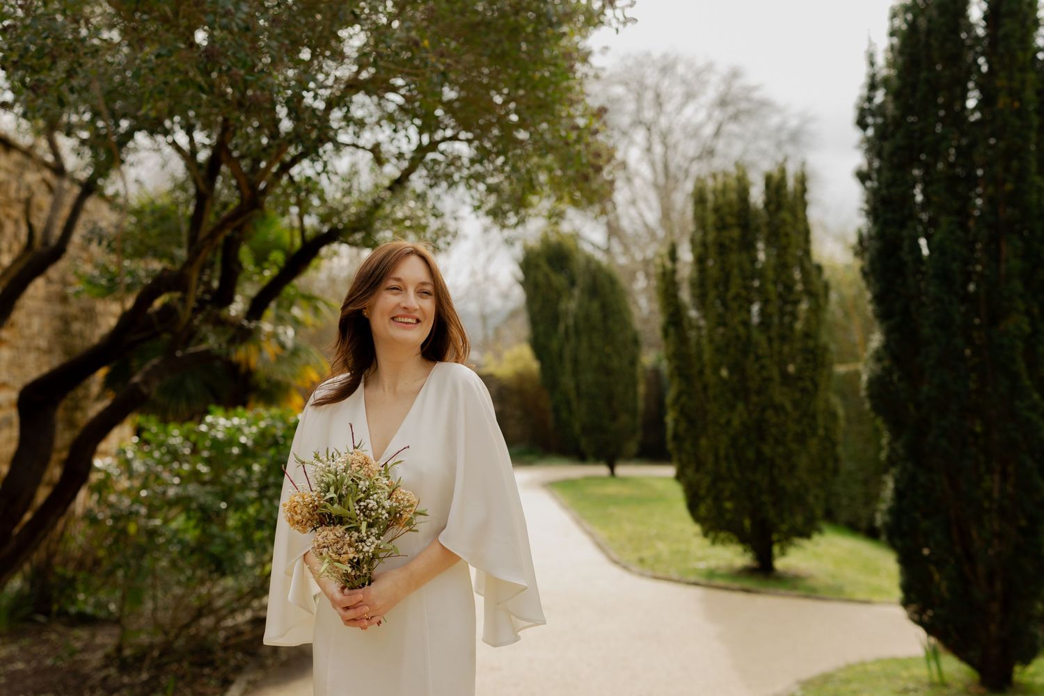 A romantic outdoor wedding scene with cypress trees and natural lighting in a garden setting.