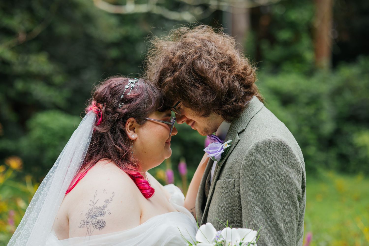 An intimate moment between newlyweds in a garden setting with purple flowers.
