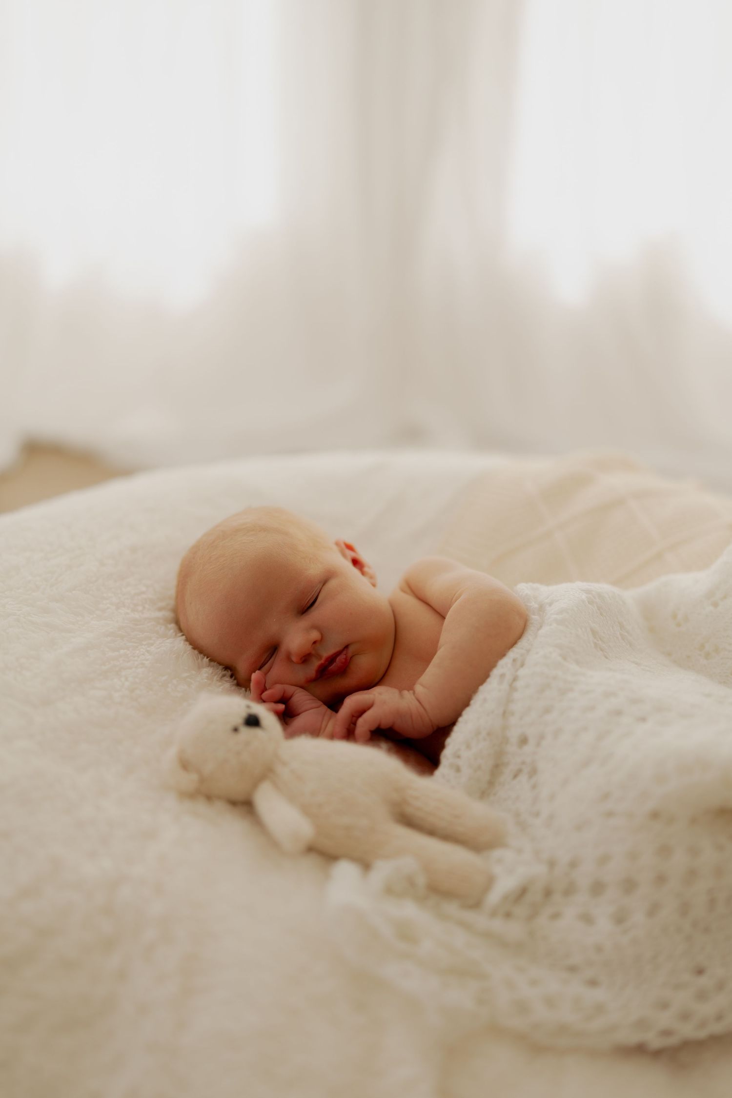 A sleeping newborn baby wrapped in soft white knit blanket shown from multiple angles in a series of photos.