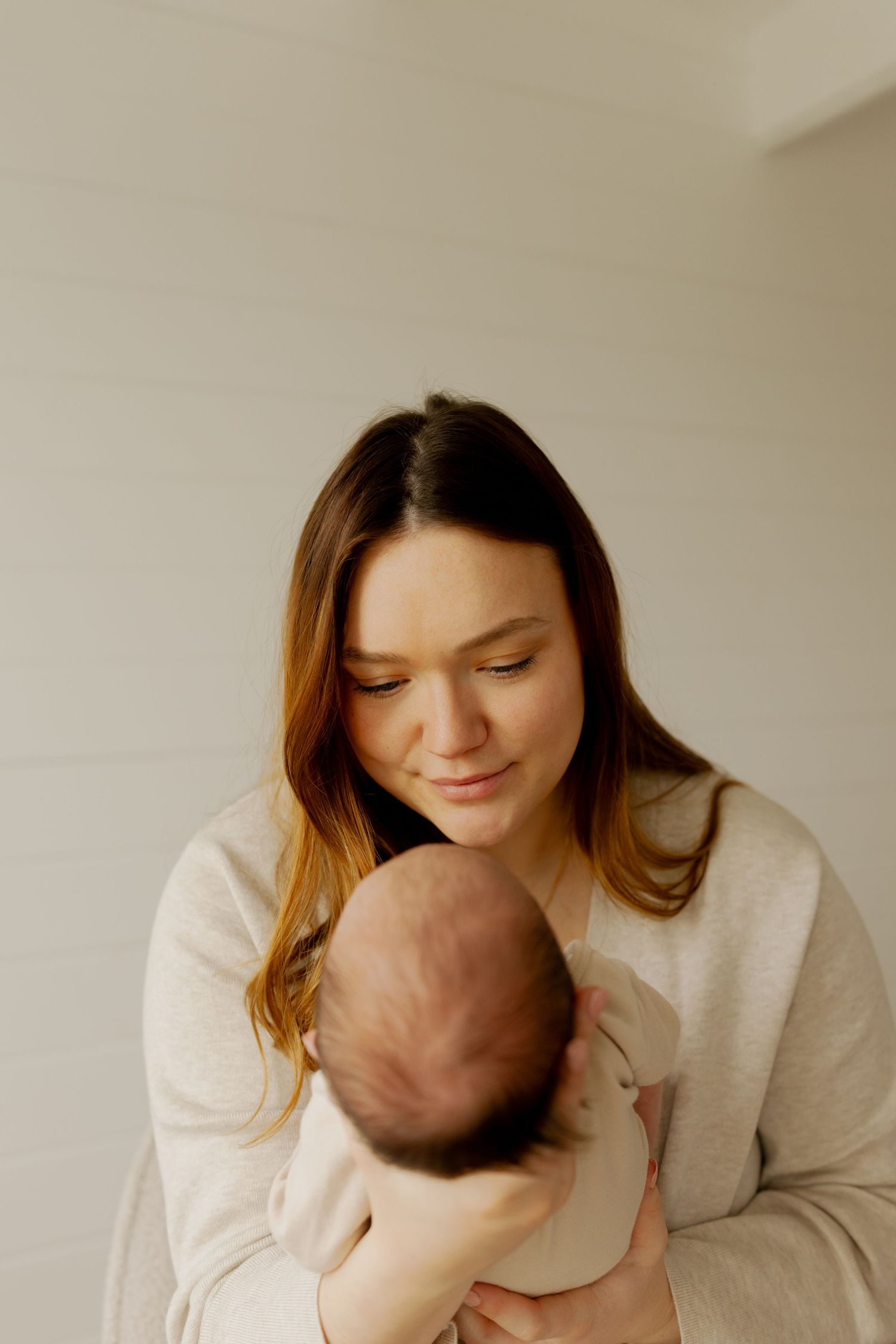 A series of four tender moments showing a parent in white clothing holding and bonding with their newborn baby.