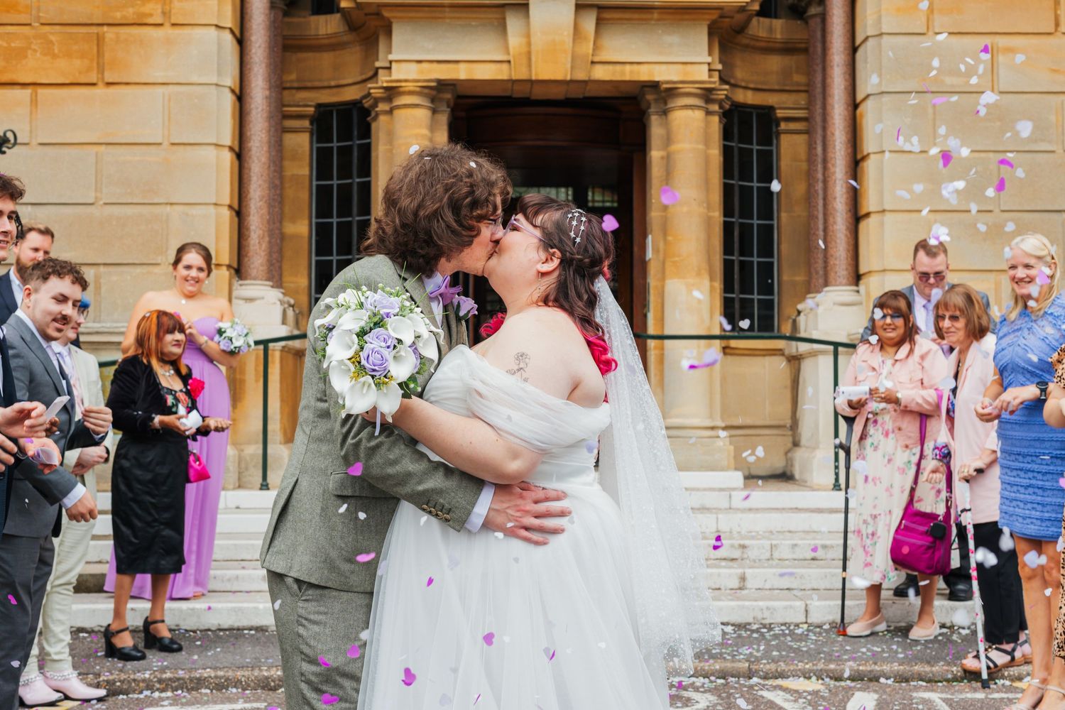 Wedding celebration with confetti outside a historic stone building.