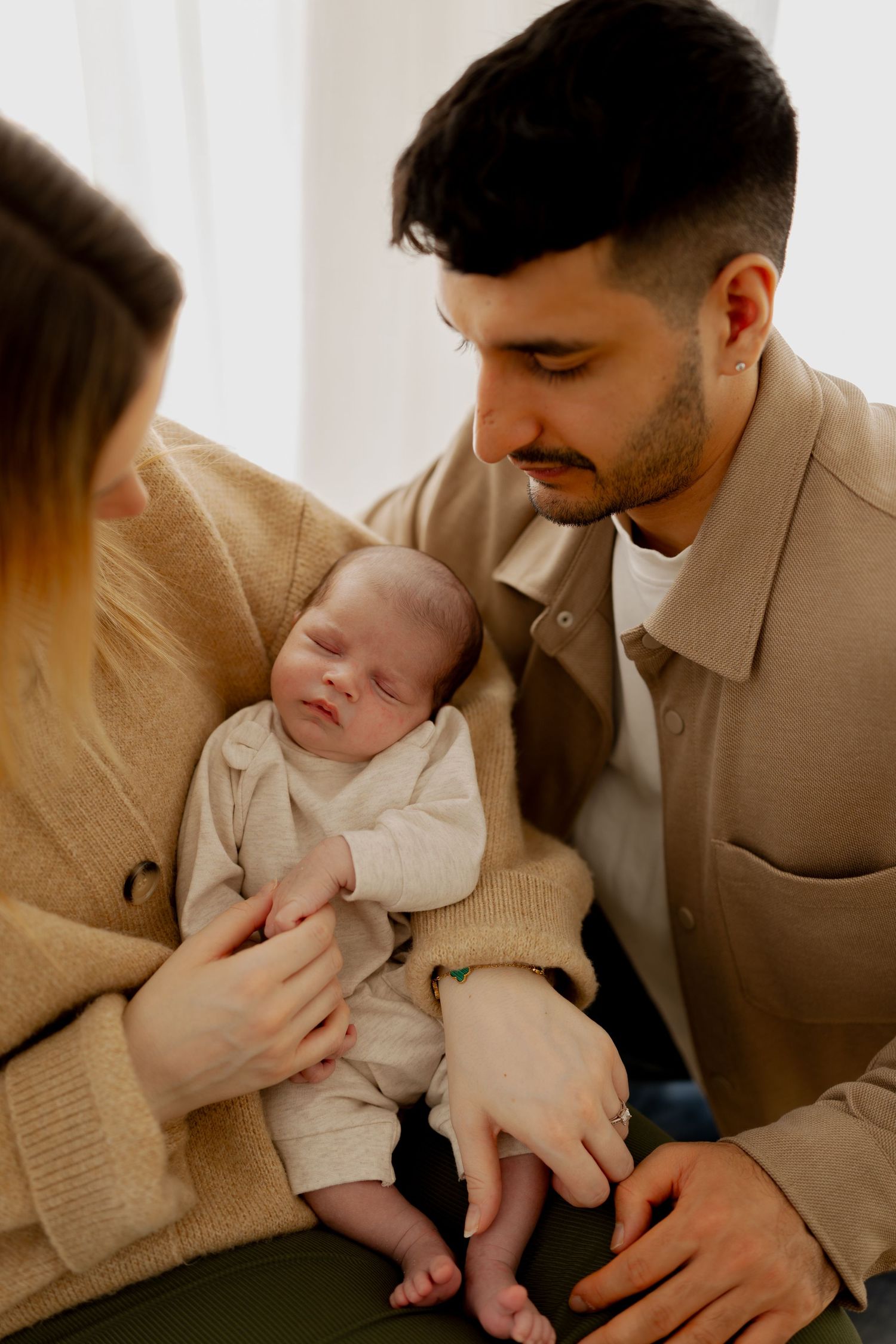 A series of tender moments between parents and their newborn baby in warm, neutral-toned indoor photos.