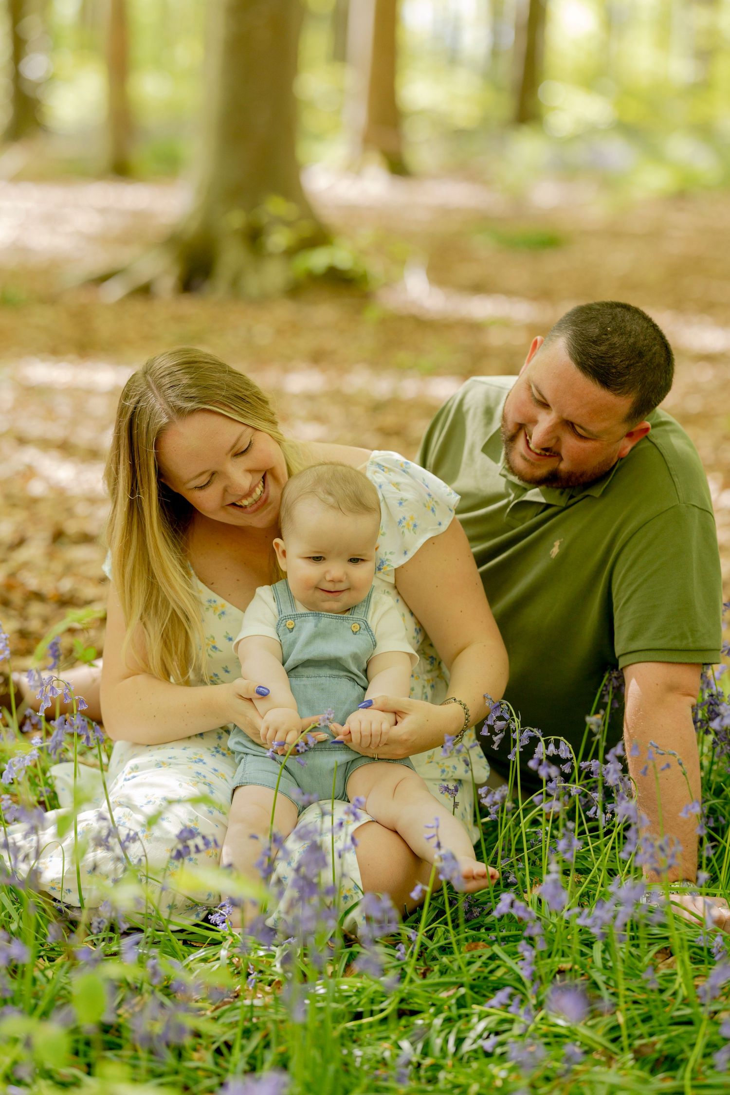 Family shares joyful moment together among blooming bluebells in spring woodland.