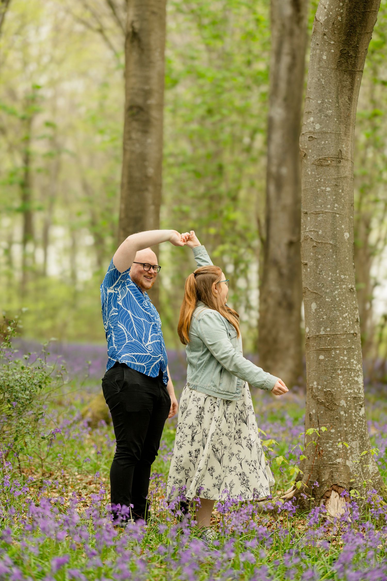 A couple dances together in a bluebell forest during springtime.