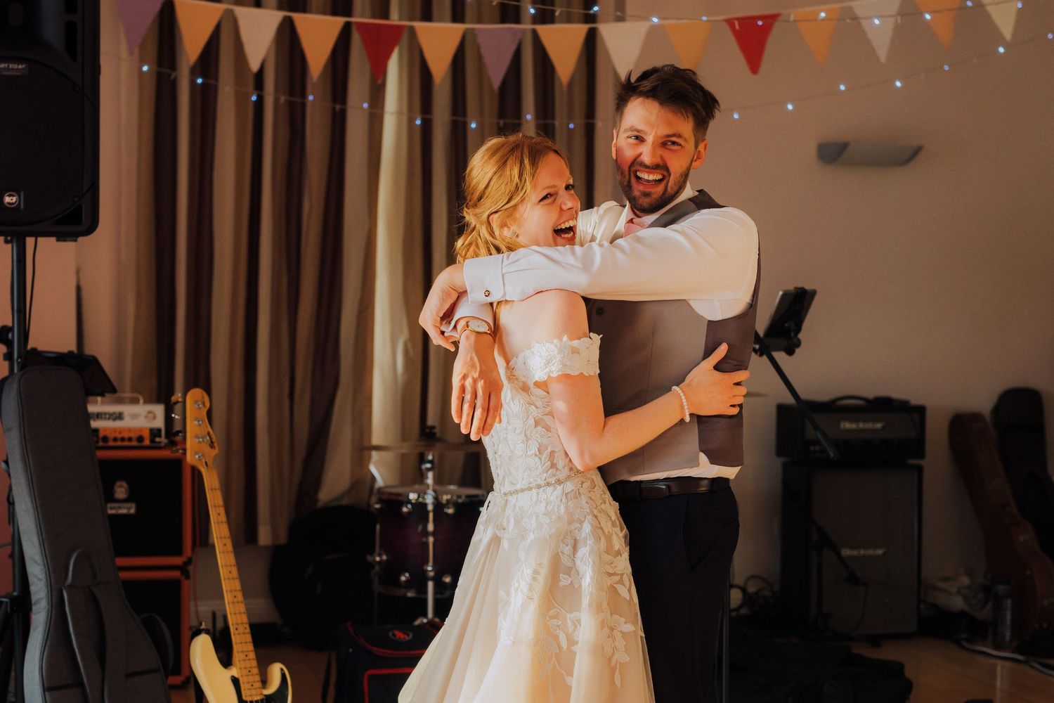 Couple sharing their first dance at a wedding reception with decorative bunting in the background.