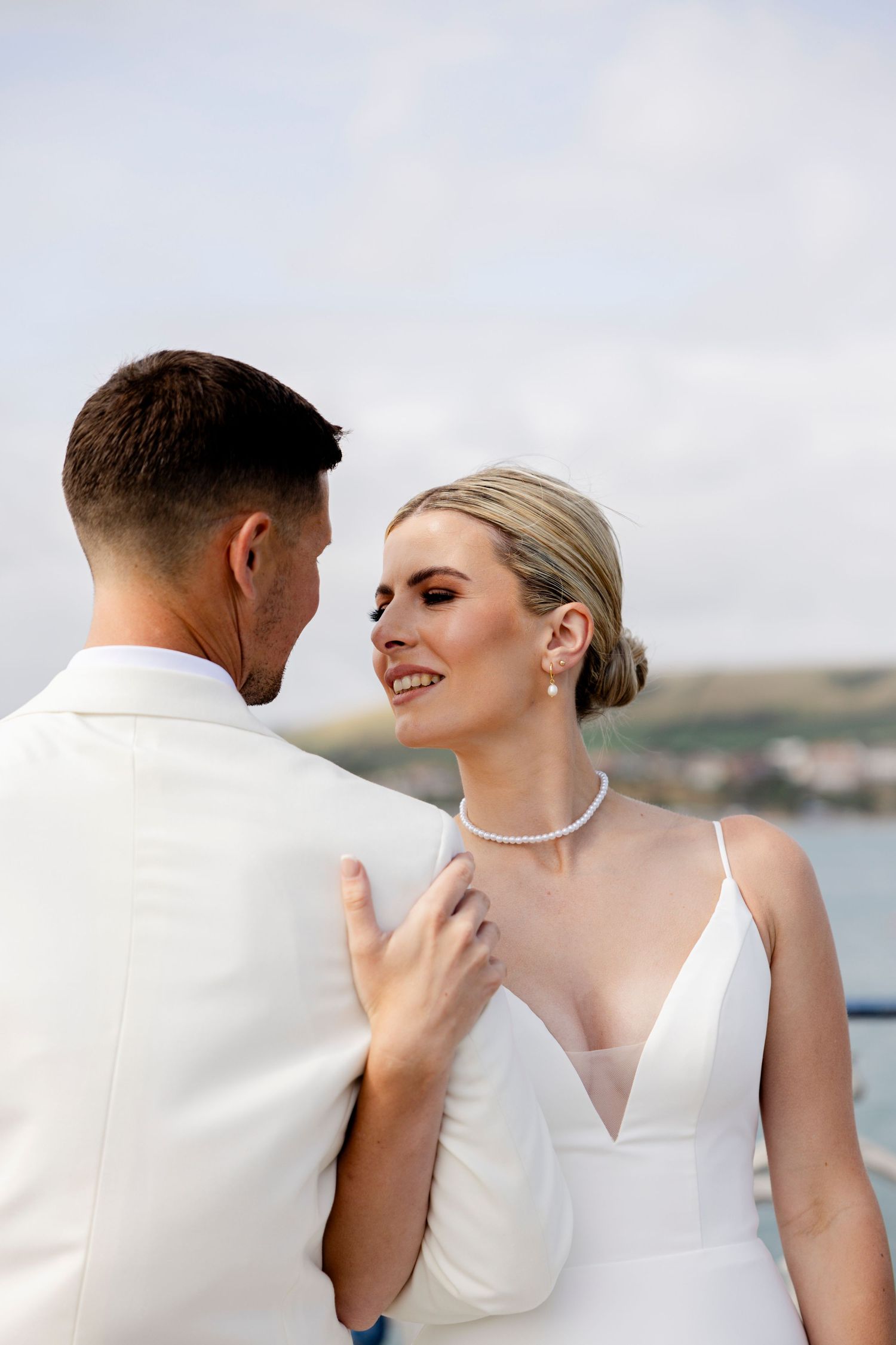 An intimate moment between a wedding couple against a coastal backdrop.