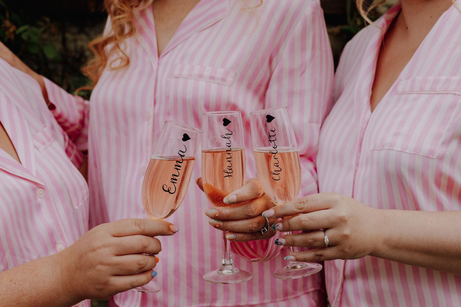 People in pink striped robes holding champagne glasses for a wedding toast.