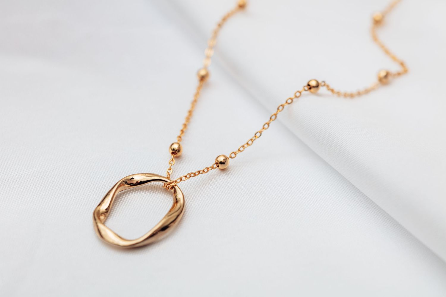 Elegant rose gold horseshoe pendant necklace displayed on white marble background.