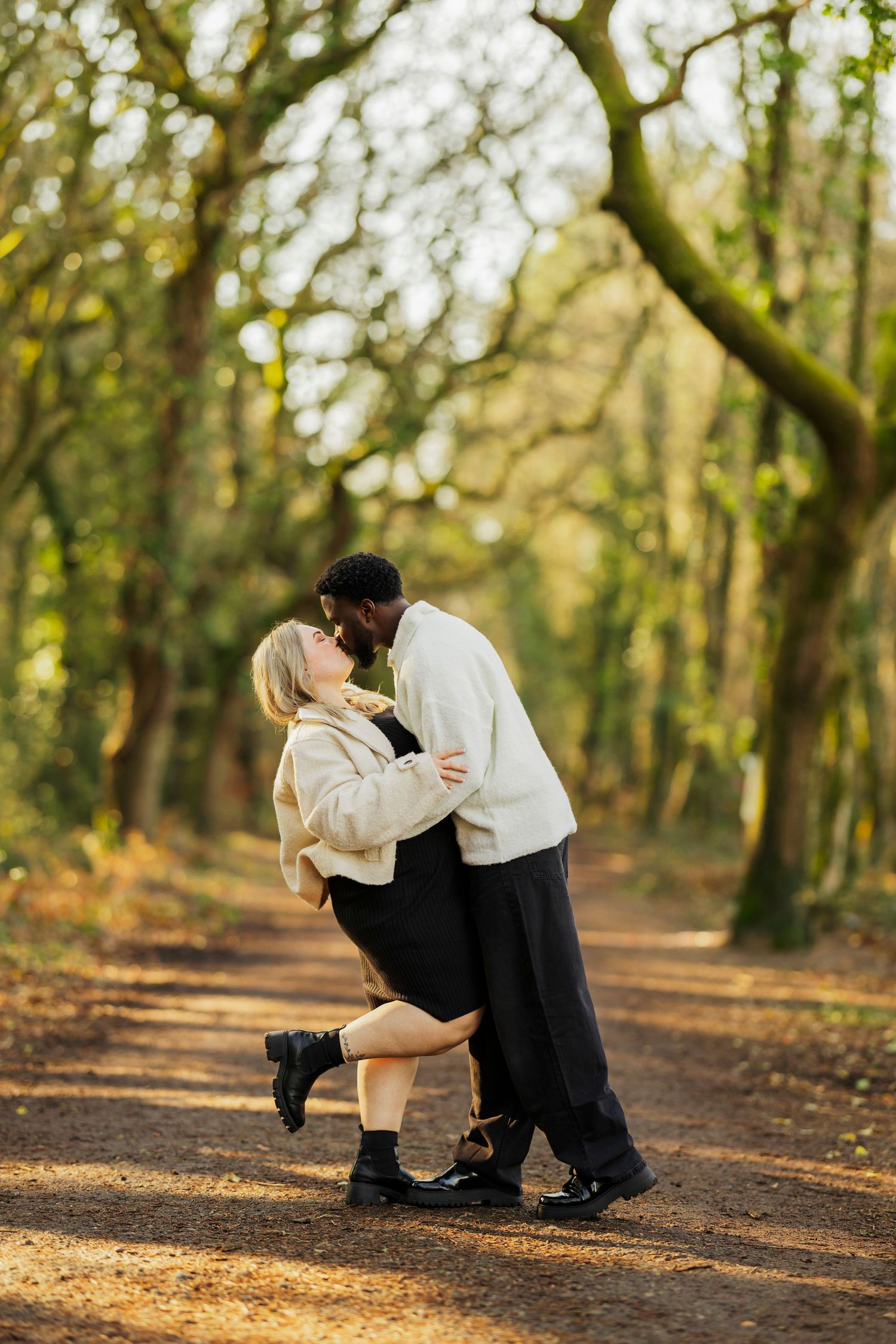 Couple embracing on a wooded path during a romantic autumn afternoon.