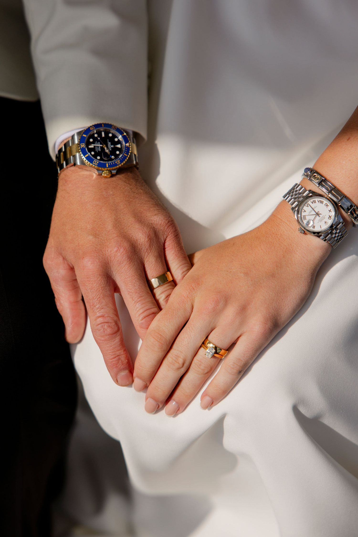Close-up of newlyweds' hands showing wedding rings and luxury watches.