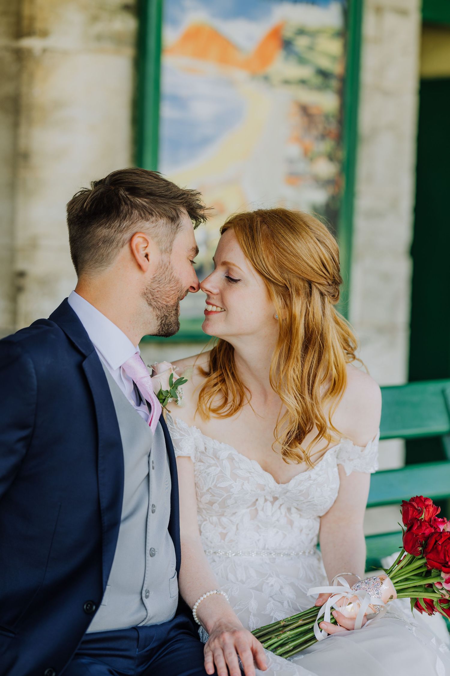 A tender moment between newlyweds sharing an intimate pose against a painted backdrop.