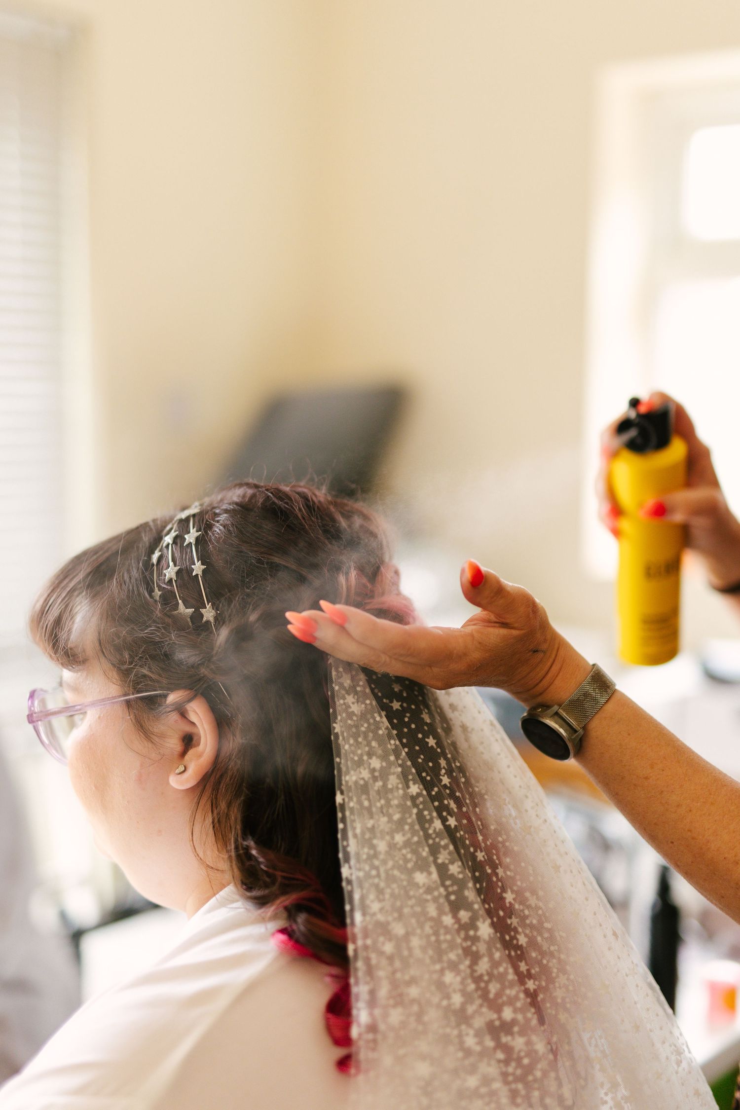 Hair styling preparation with hairspray being applied during wedding preparations.