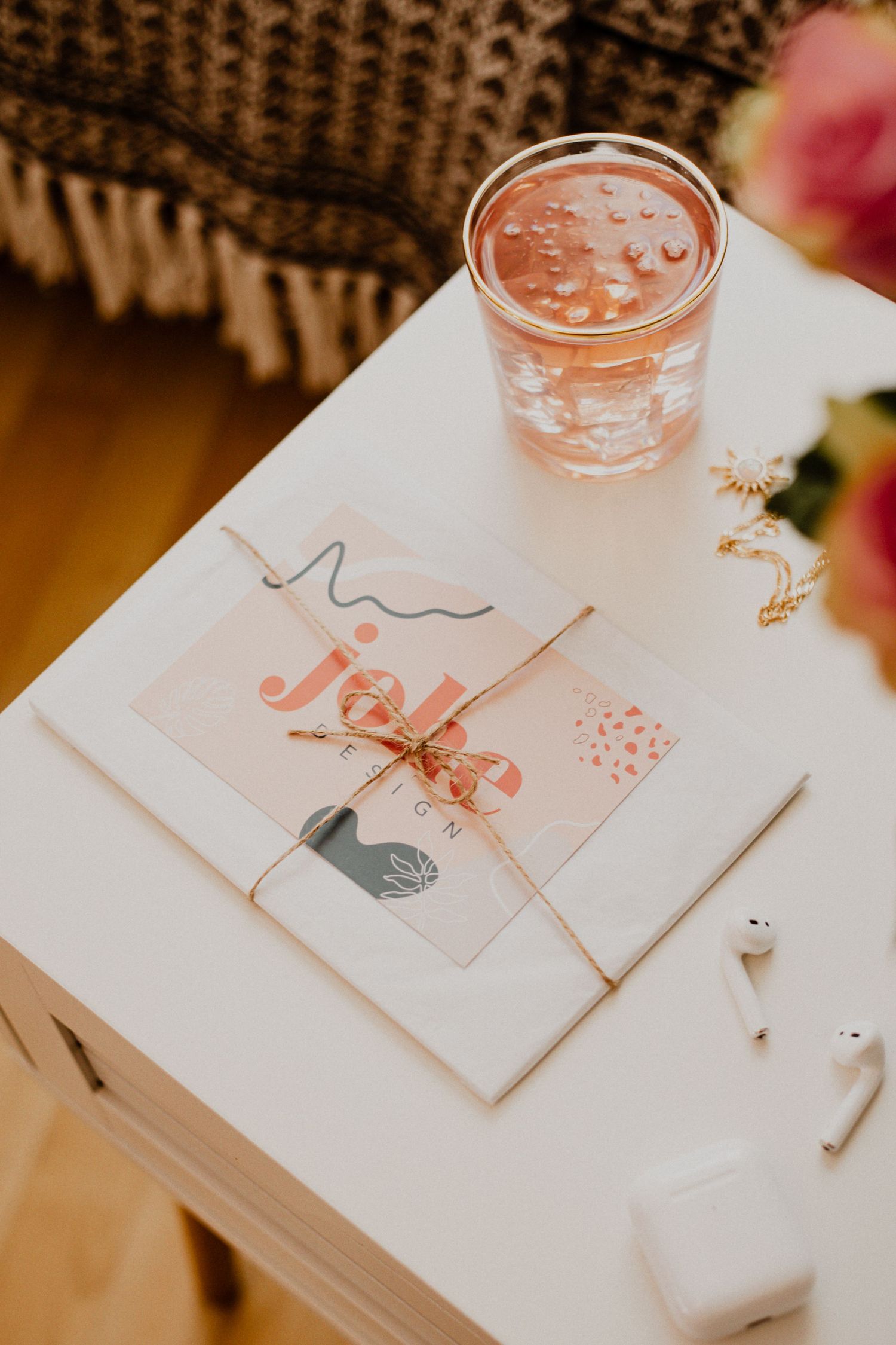 Pink smoothie drink in clear glass on white surface with decorative paper items and hand-drawn illustrations.