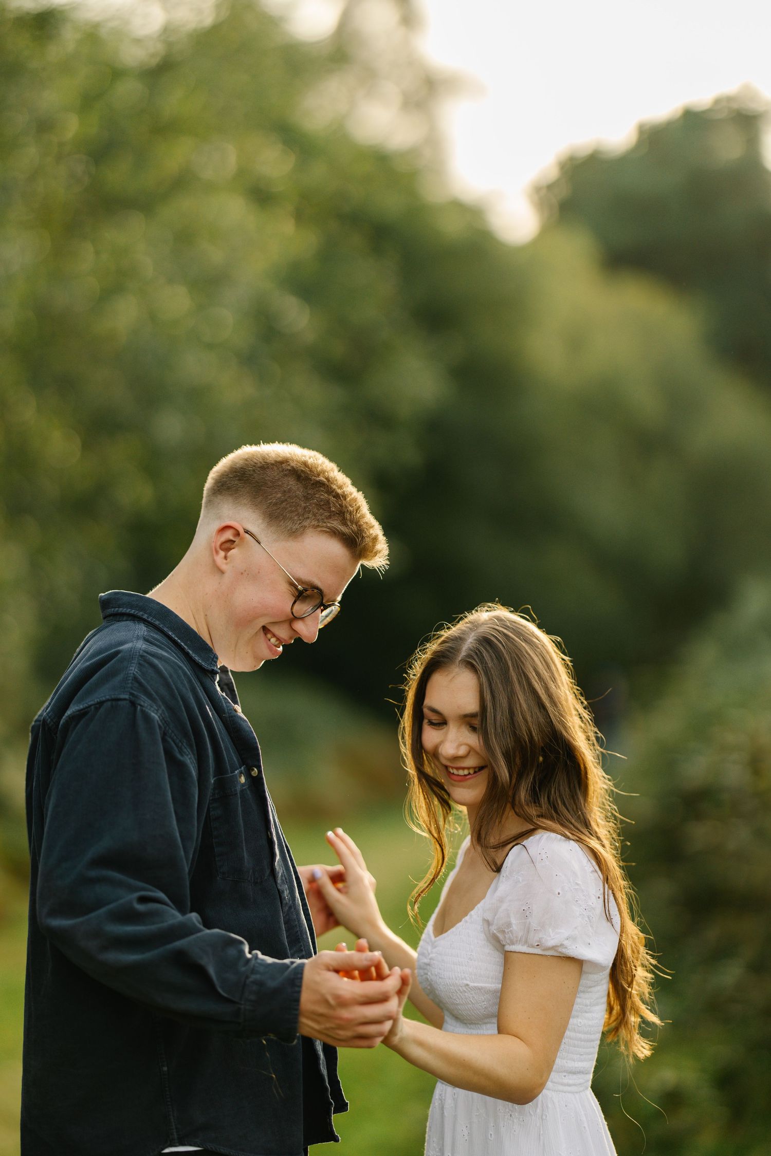 A couple shares an intimate moment while standing in a sunlit garden setting.