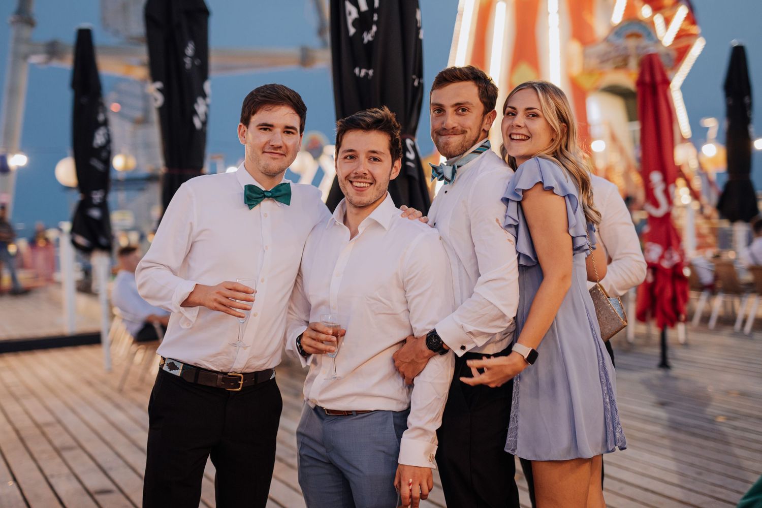 Group of friends posing together on a pier at sunset.