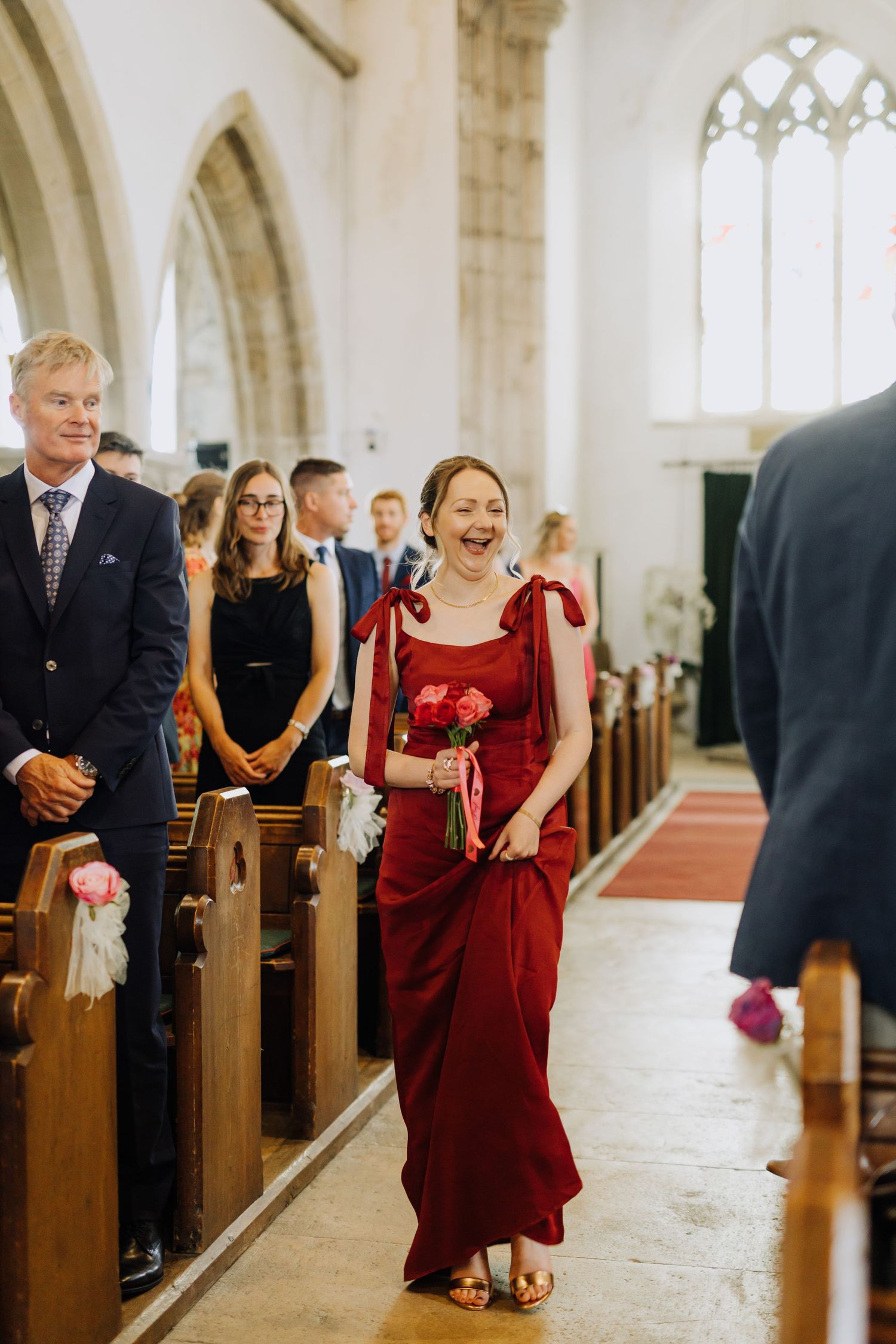 Wedding guests and attendants smiling during a traditional church ceremony procession.