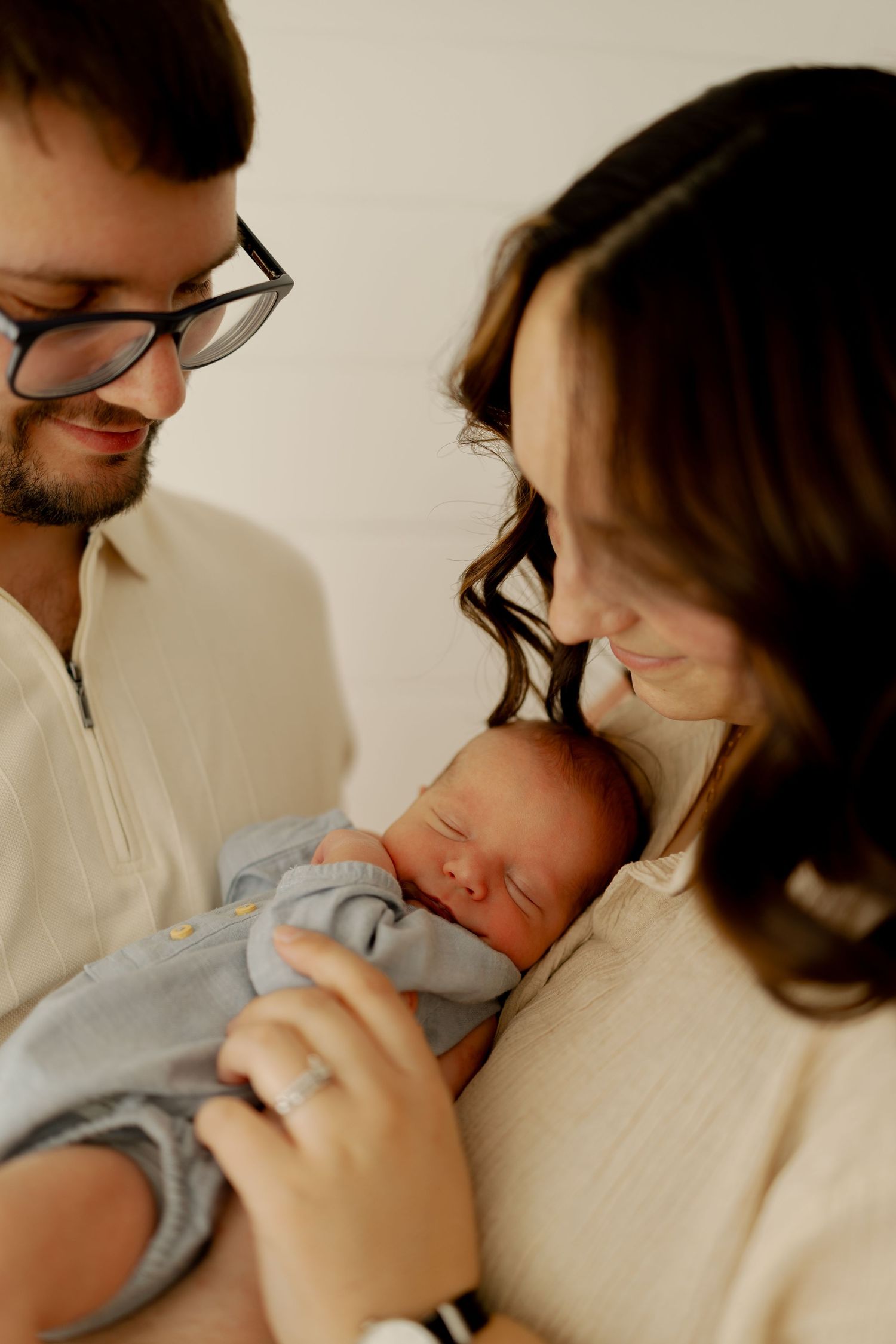 A series of tender moments showing parents cradling and bonding with their sleeping newborn baby in soft lighting.