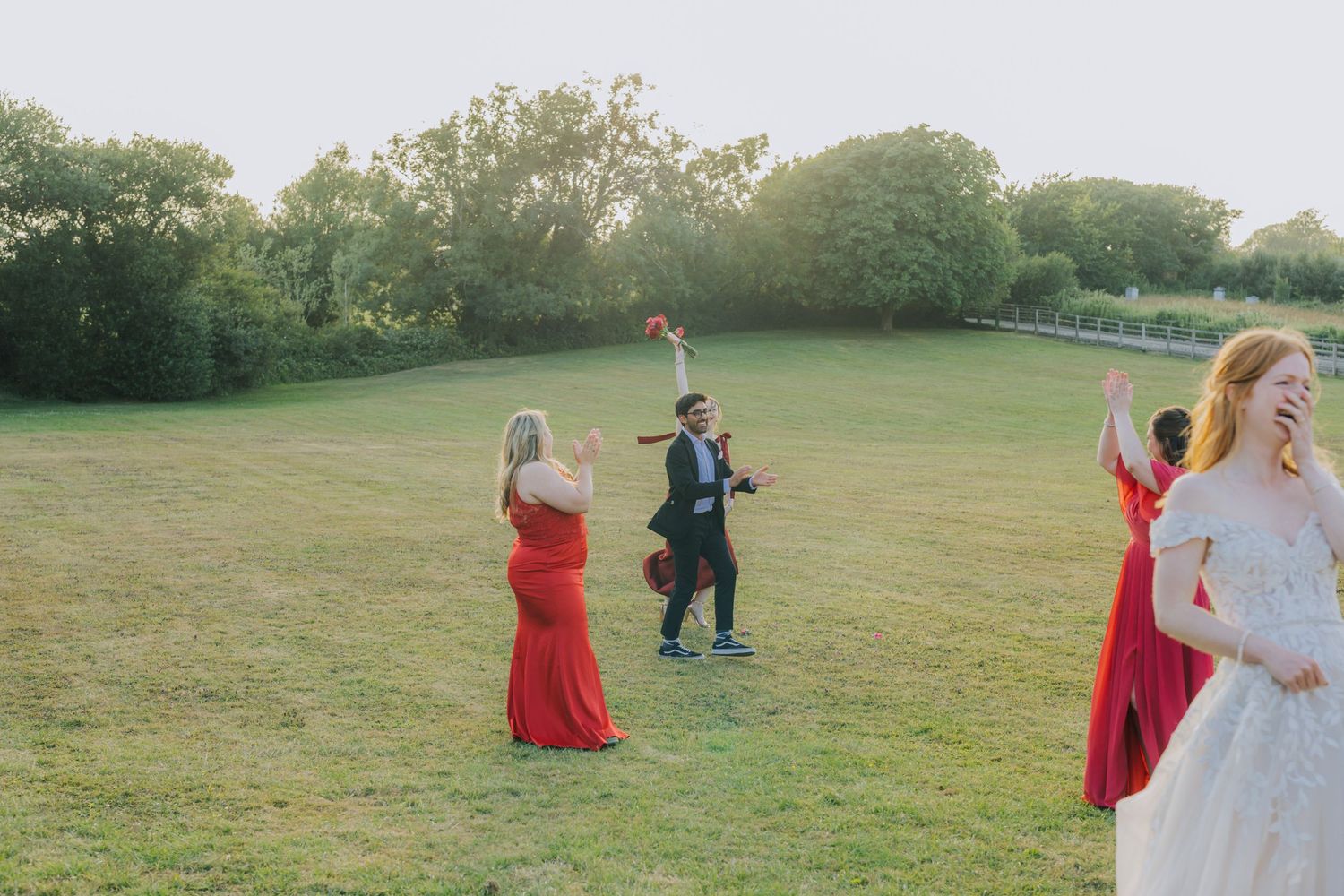 Wedding party celebrating on a grassy lawn on a sunny afternoon.