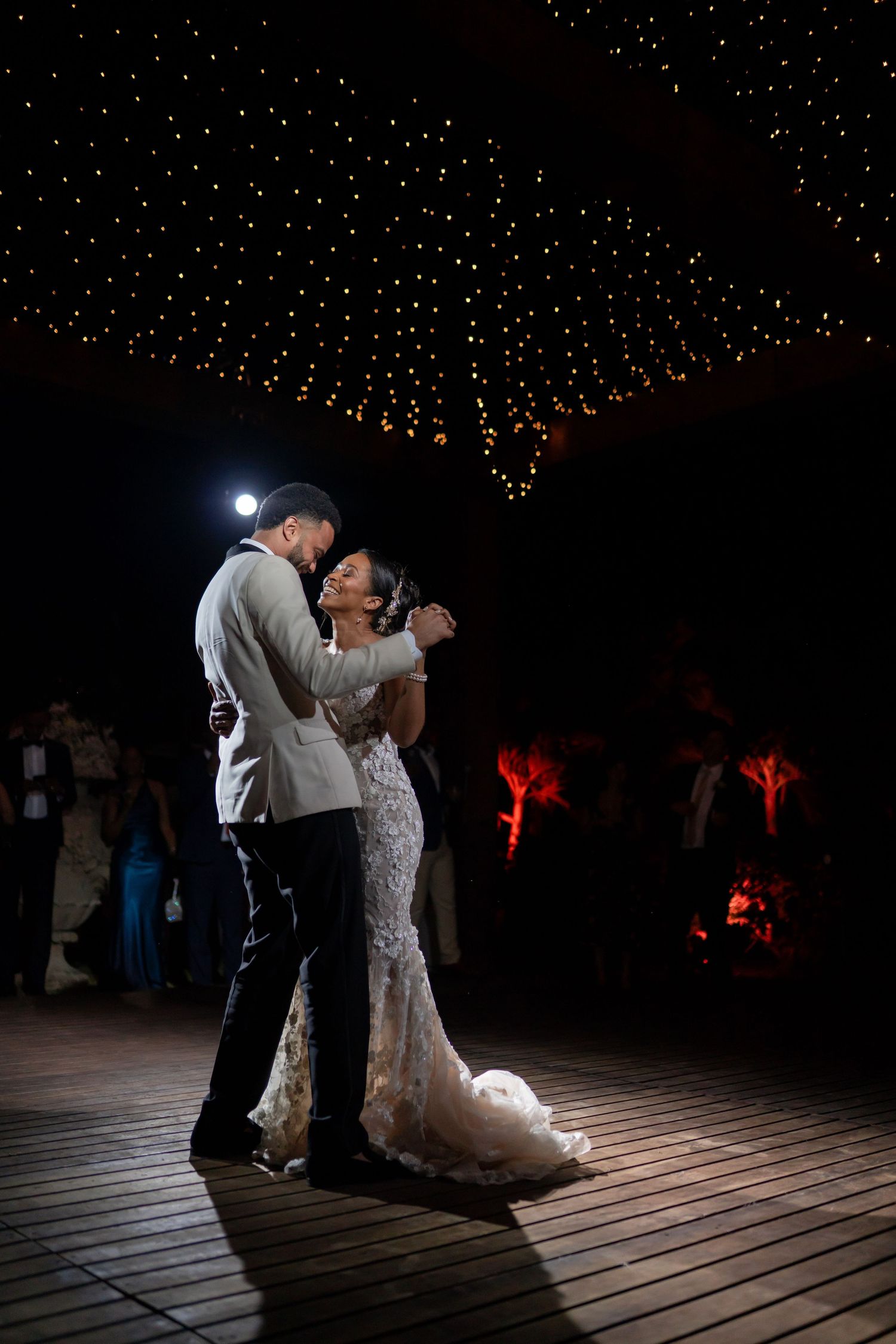 A couple dances together during an intimate first dance at their wedding reception under dramatic lighting.