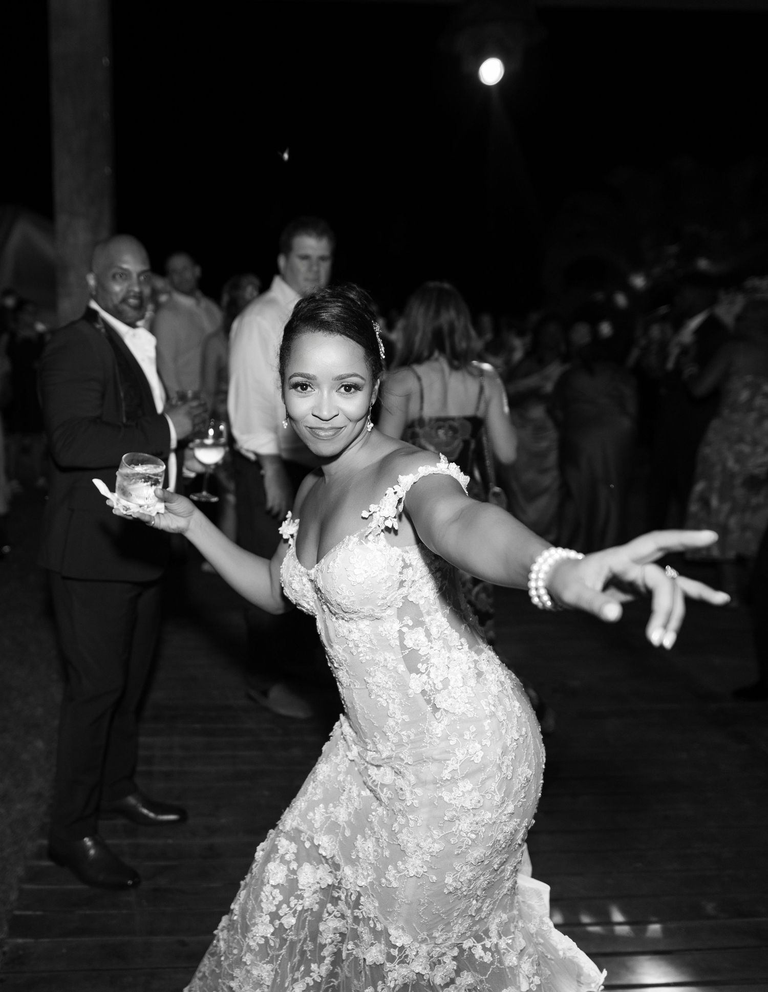 A joyful guest in a white lace dress dances energetically at an evening reception or party.