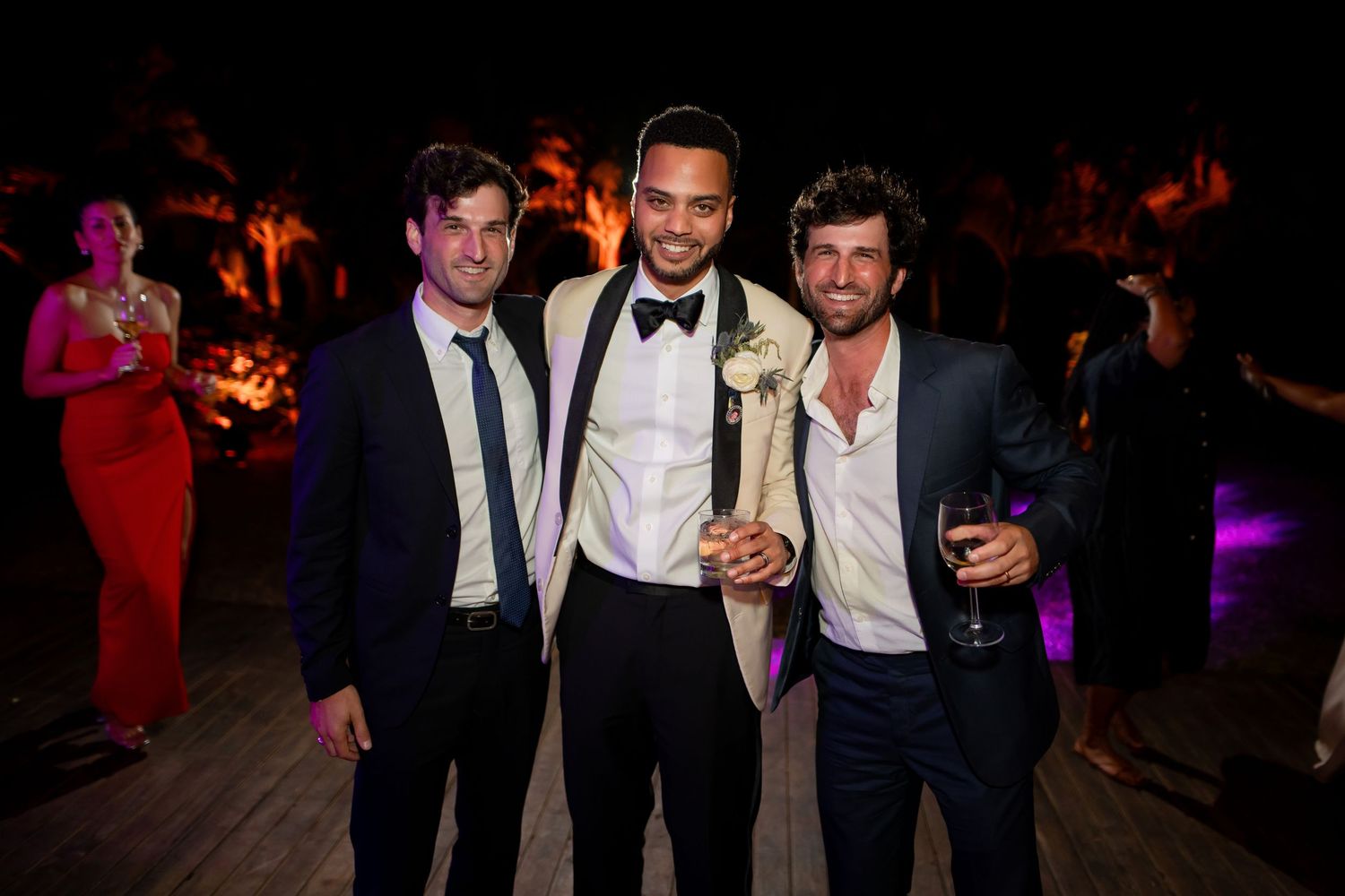People in formal attire pose together and smile during an evening celebration event.