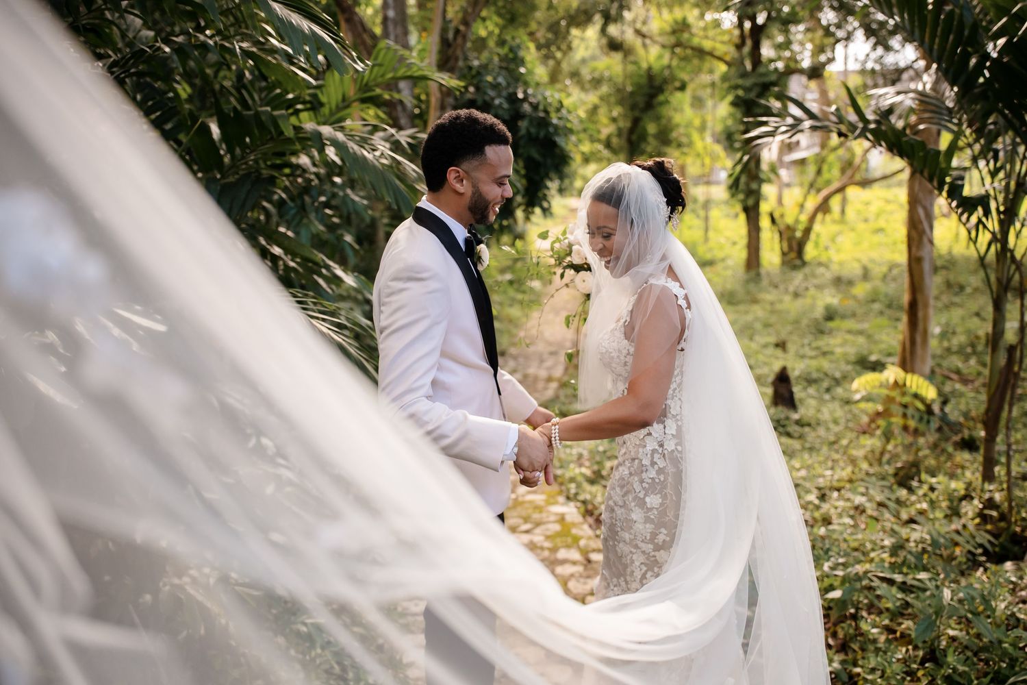 A romantic outdoor wedding scene with a flowing white veil captured in a lush garden setting.