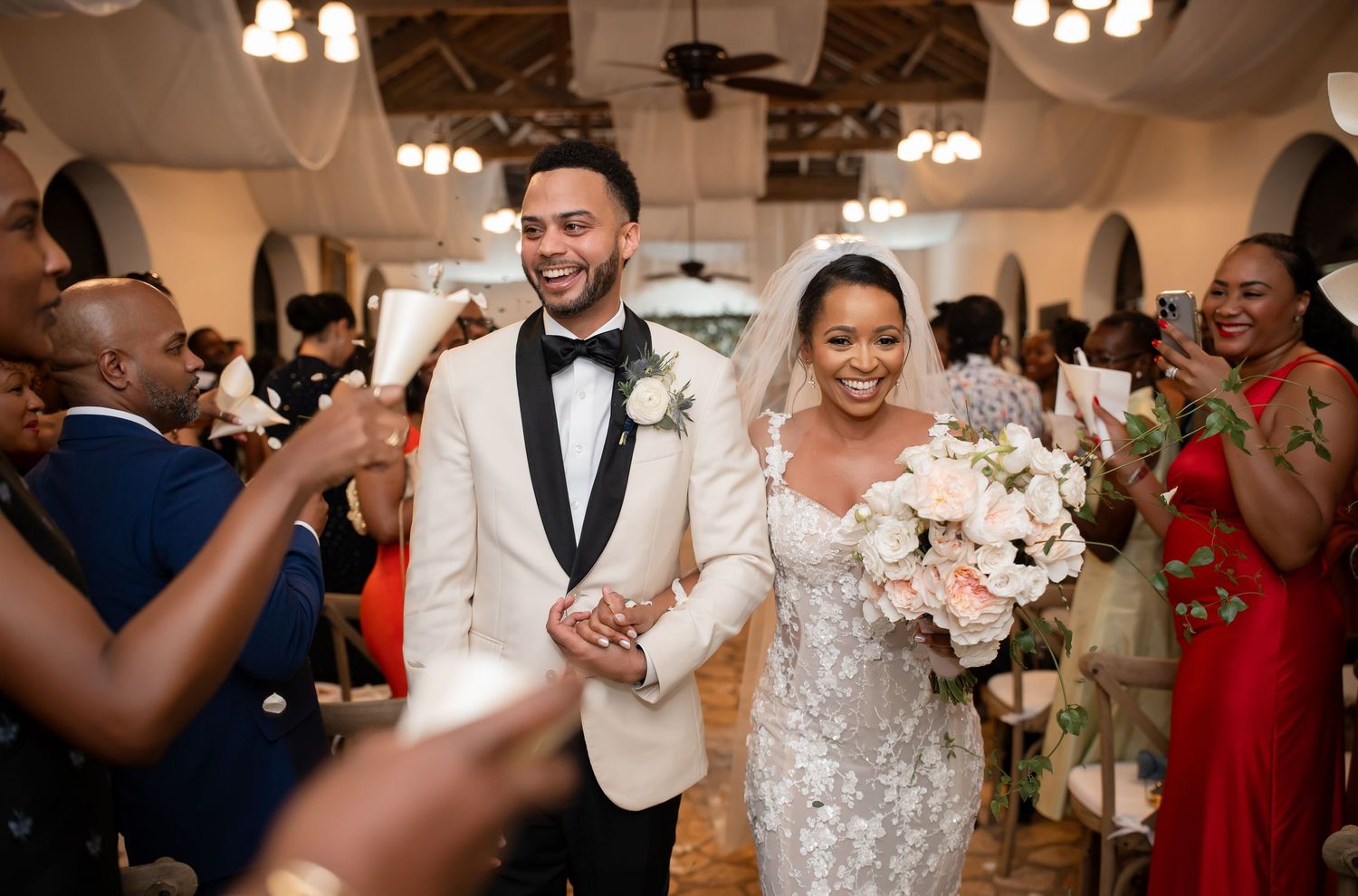A bride and groom share their first dance at a glamorous ballroom wedding reception surrounded by guests.