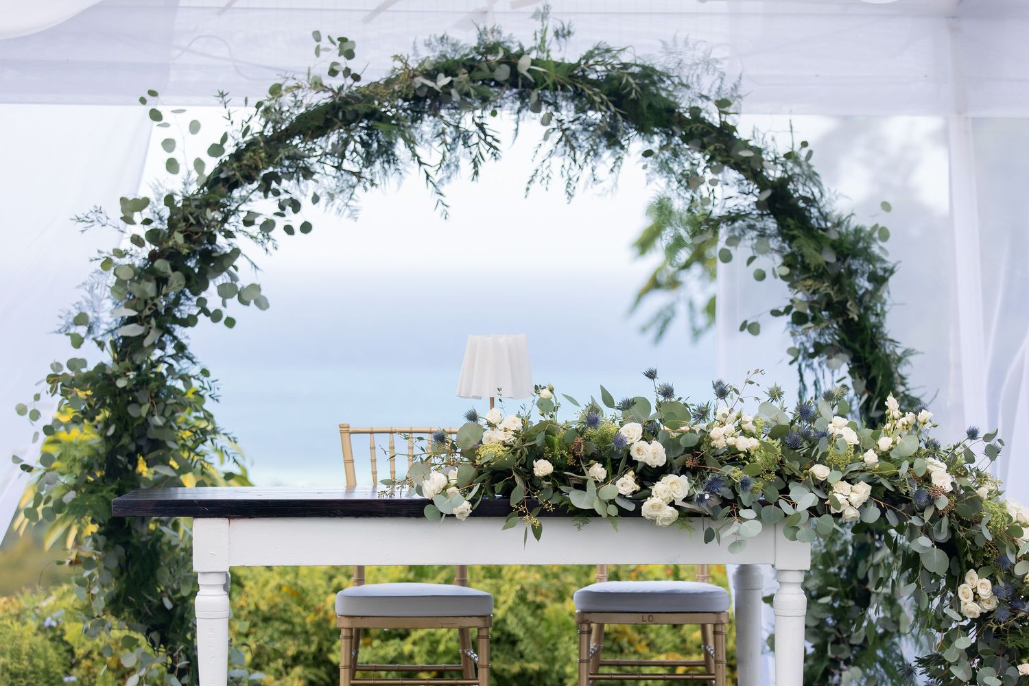 A string of wedding ceremony images showing an elegant floral arch and white chairs set up outdoors against a cloudy sky.