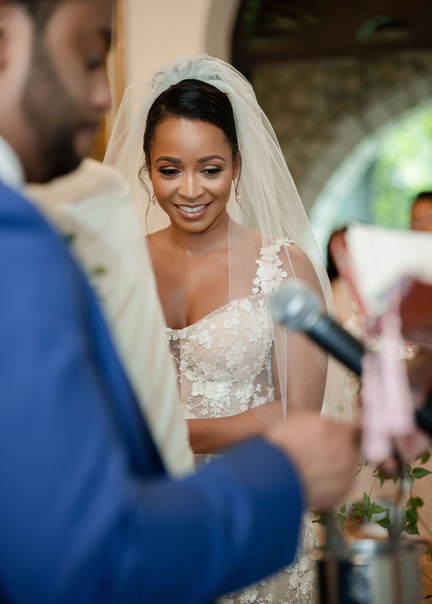 A close-up view of a happy bride in a delicate lace dress and veil during the wedding ceremony.
