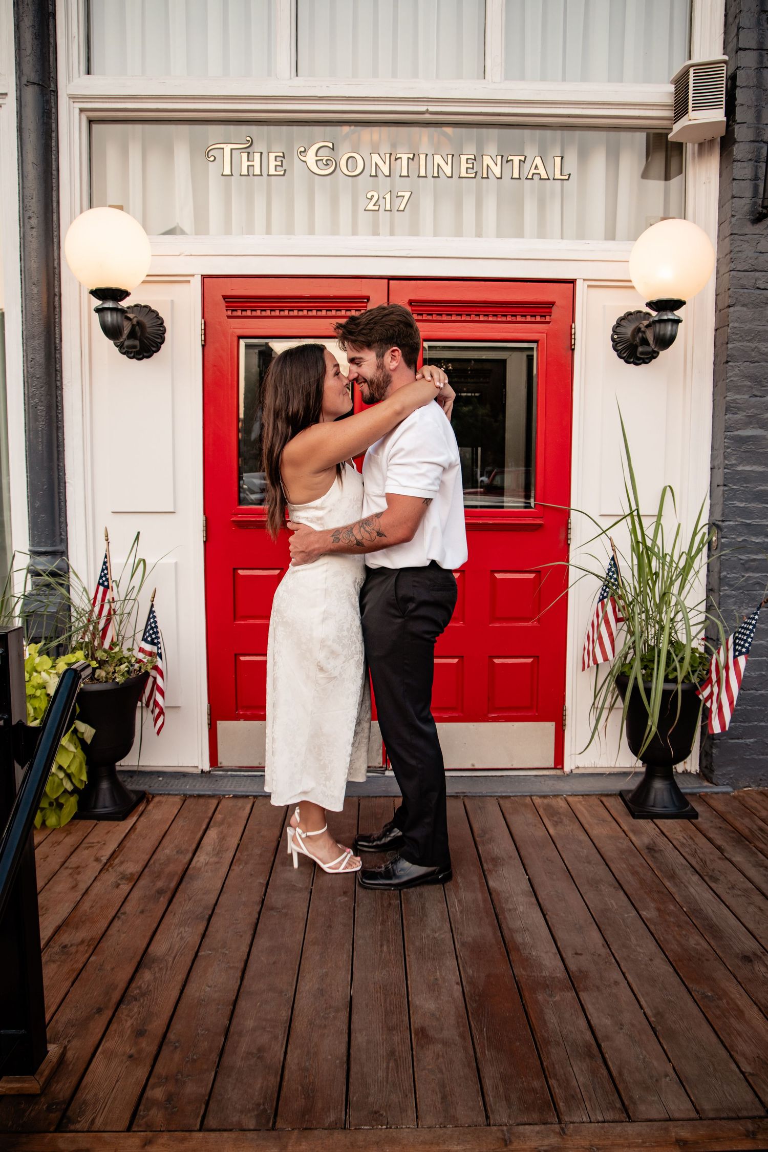 Couple sharing a romantic kiss in front of The Continental restaurant at 217, decorated with American flags.